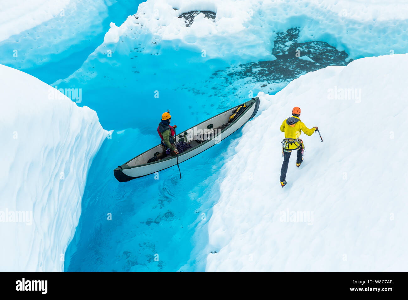 Auf der Matanuska Gletscher, einem großen blauen See sitzt auf dem Gletscher Eis. Im See ein Kanu Transporte zwei Bergsteiger über dem blauen Wasser. Man steht ein Stockfoto
