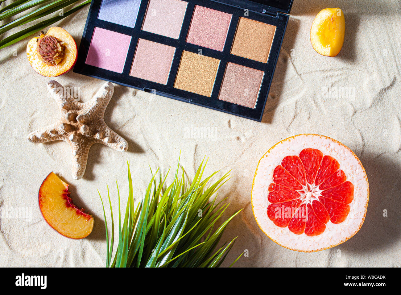 Bezaubernden Strand. Die Palette der Schatten mit quadratischen Nachfüllungen von hellen Früchten, Korallen umgeben, und Palm Blätter liegen auf dem weißen Sand. Nahaufnahme, Ansicht von oben. Stockfoto