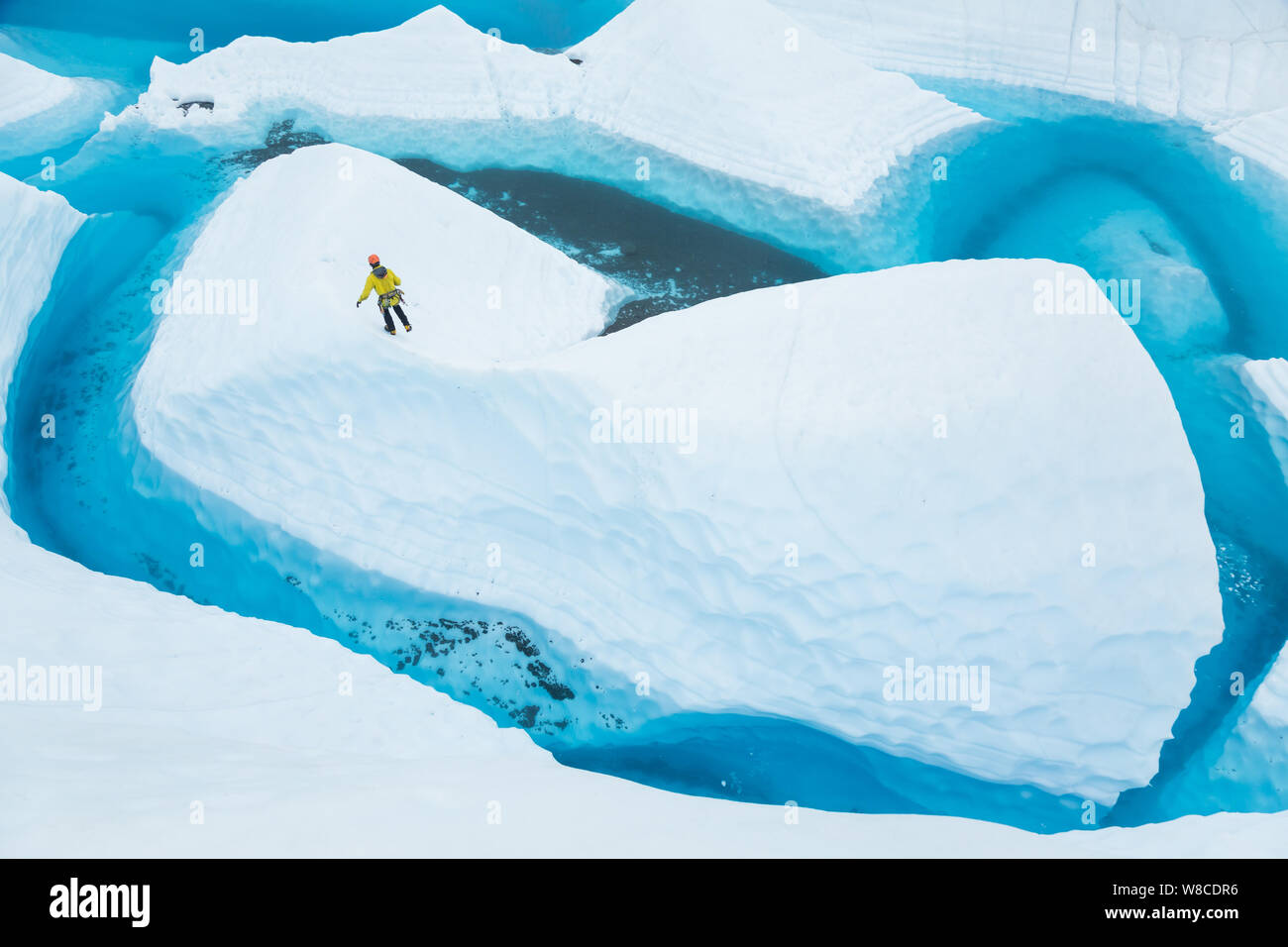 Auf der Matanuska Gletscher in Alaska, ein junger Mann geht den Grat eines Ice fin Insel auf einem Gletscher See. Stockfoto