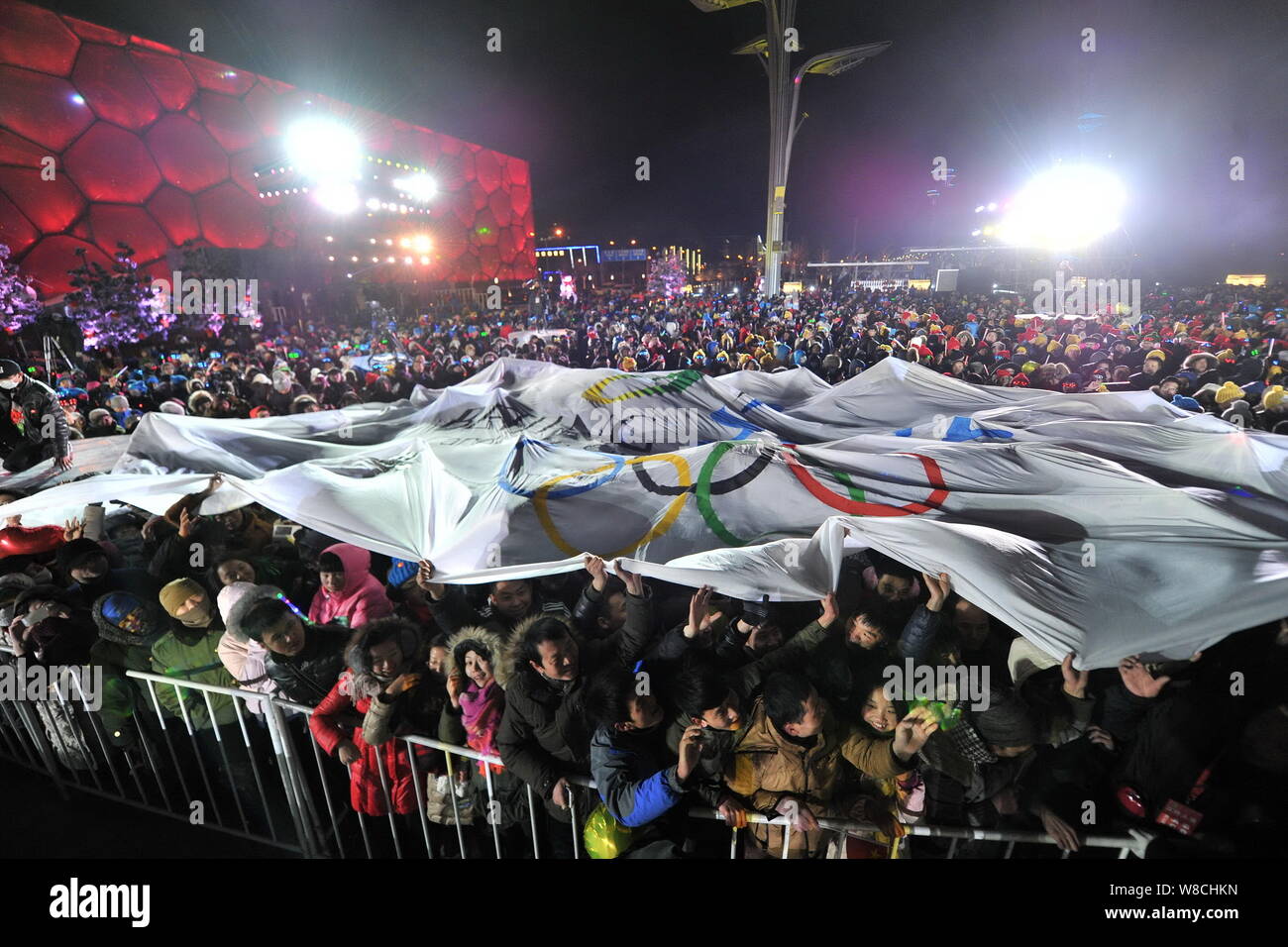 Die Chinesen halten Sie die olympische Flagge das Neue Jahr neben dem Water Cube National Aquatics Center zu feiern mit Leuchten während der "Cou Stockfoto