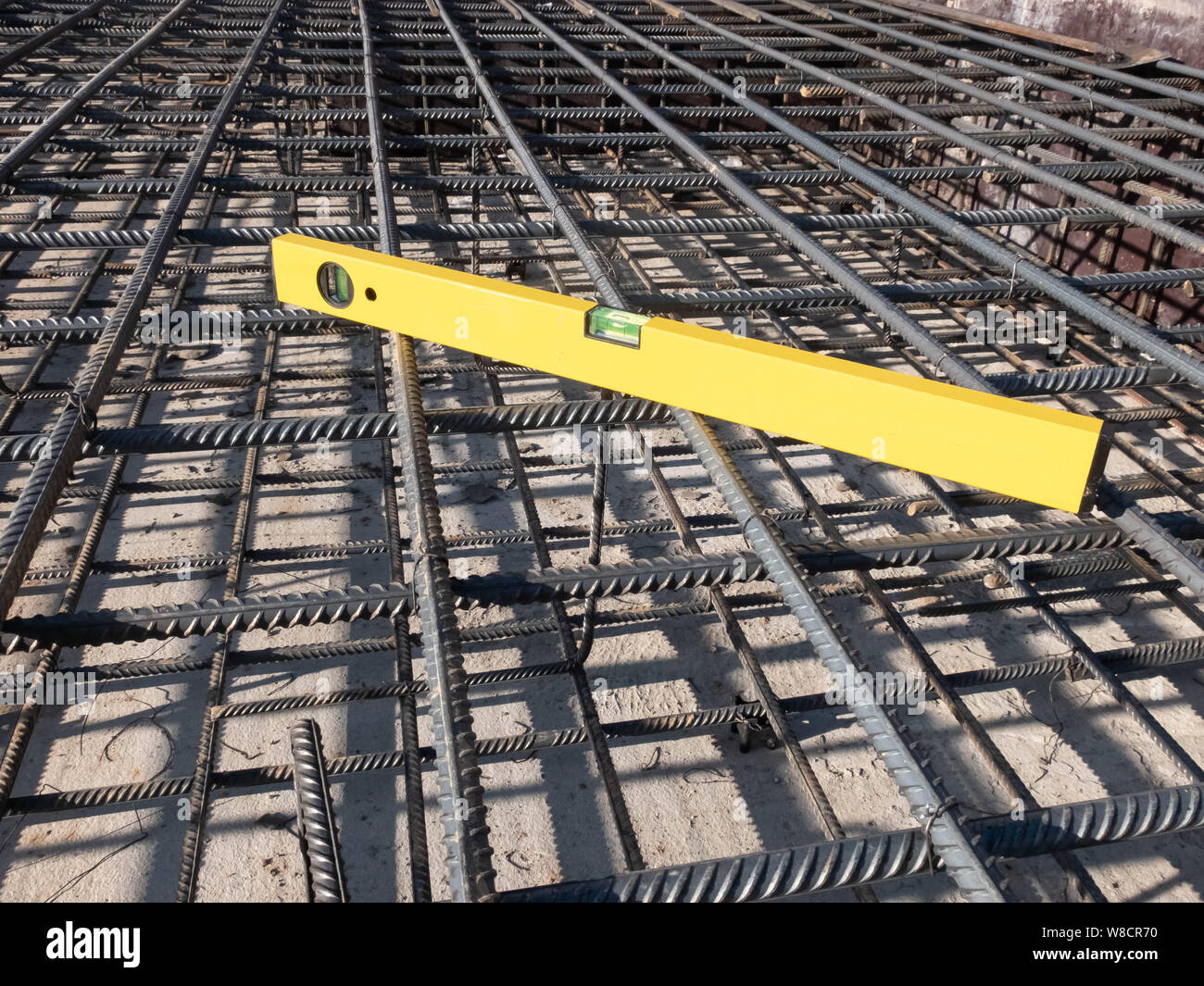 Gebäude gelb gefärbte Ebene Werkzeug auf der steel Grid der Wohngebäude Basis Verstärkung. Stockfoto
