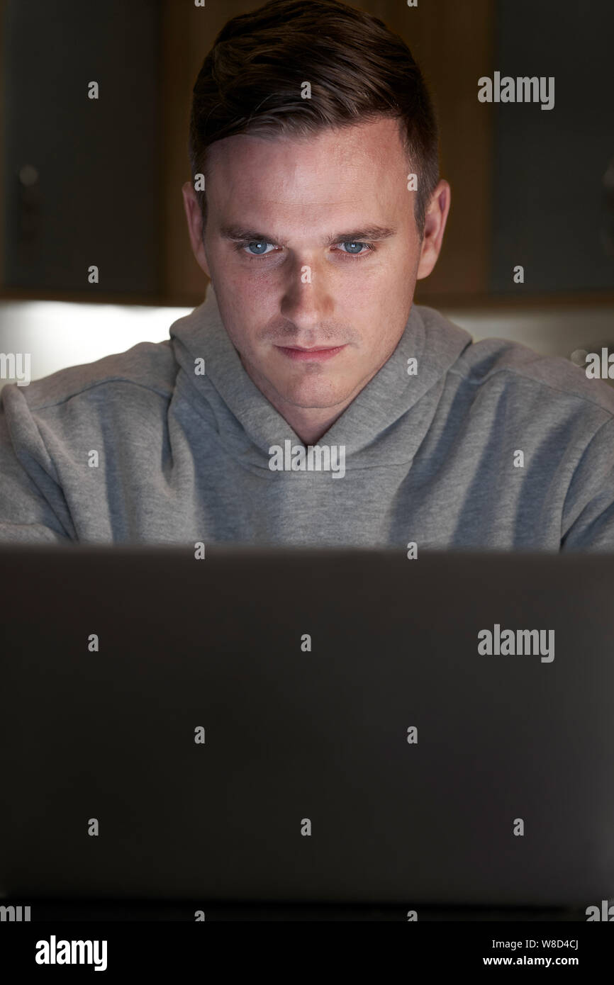 Verdächtig aussehende Mann mit Laptop in den Abend zu Hause Stockfoto