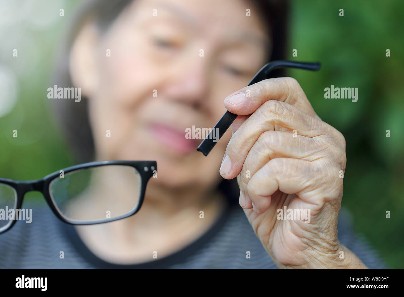 Ältere asiatische Frau reparieren gebrochene Gläser Stockfoto