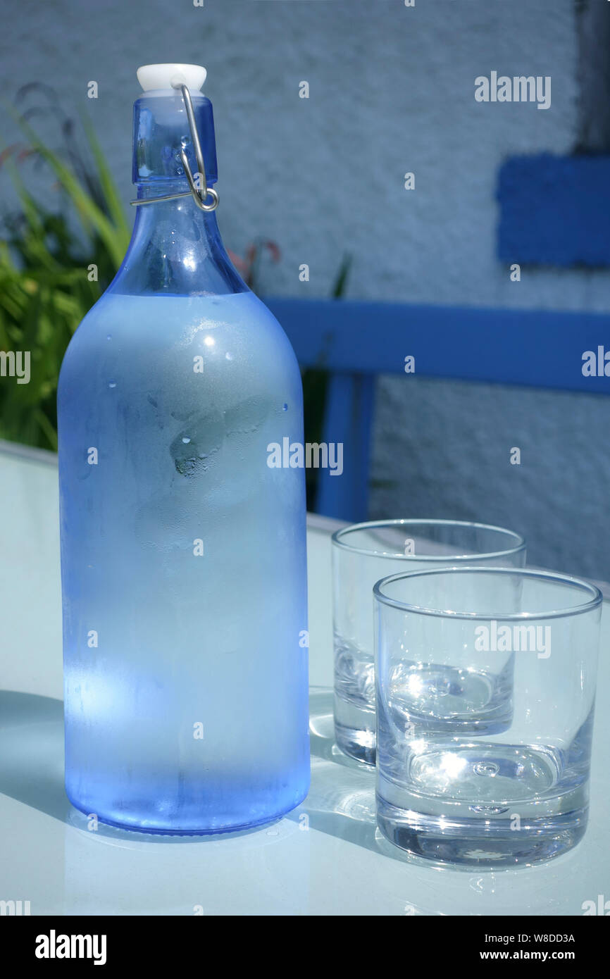 Flasche kaltes Wasser und zwei Gläser auf einen Garten Tisch tippen im Sommer Stockfoto
