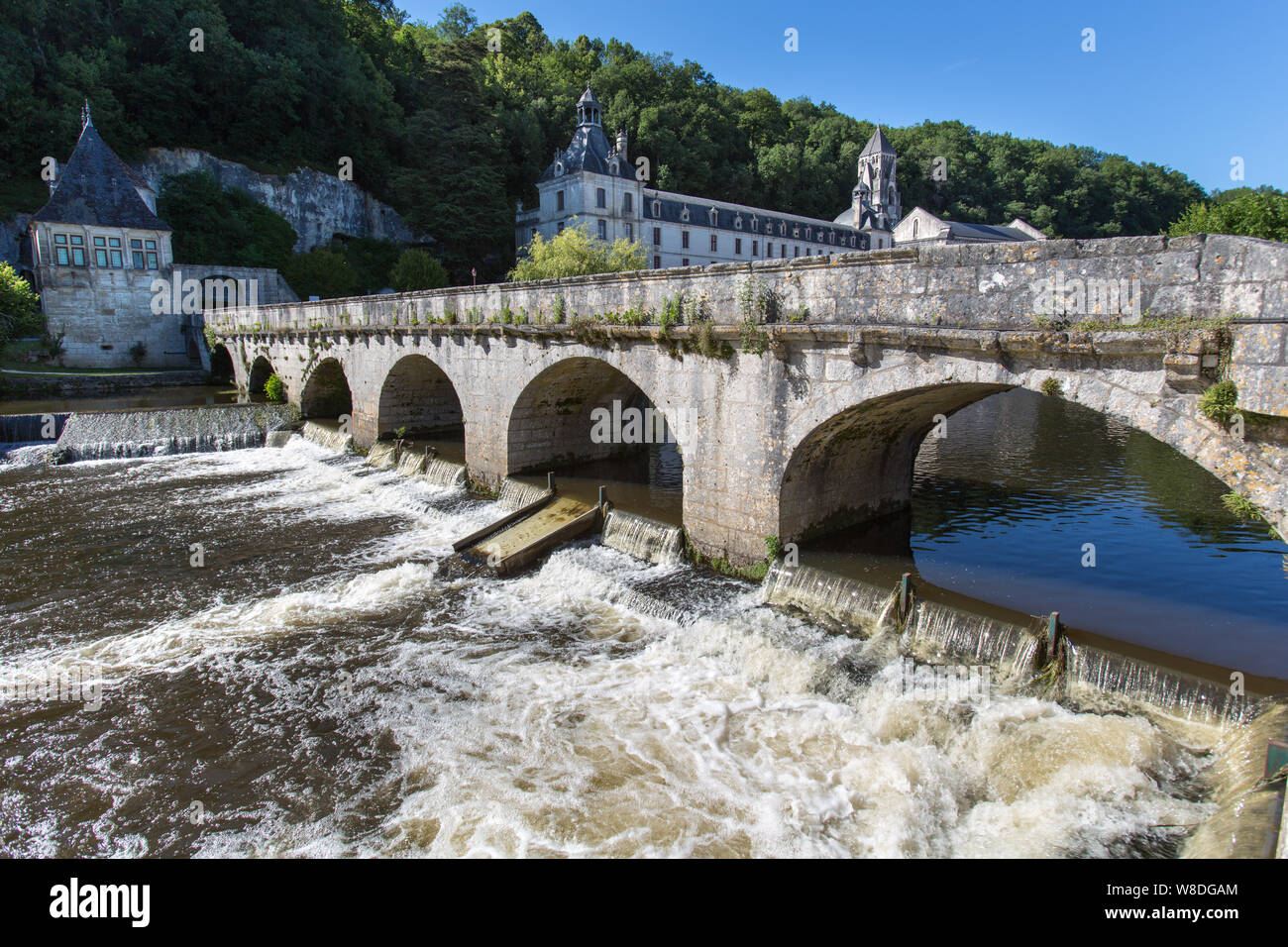 Brantome en Périgord, Frankreich. Der Pont Coude (rechter Winkel Brücke) über den Fluss Dronne, mit der Abtei von Brantome im Hintergrund. Stockfoto