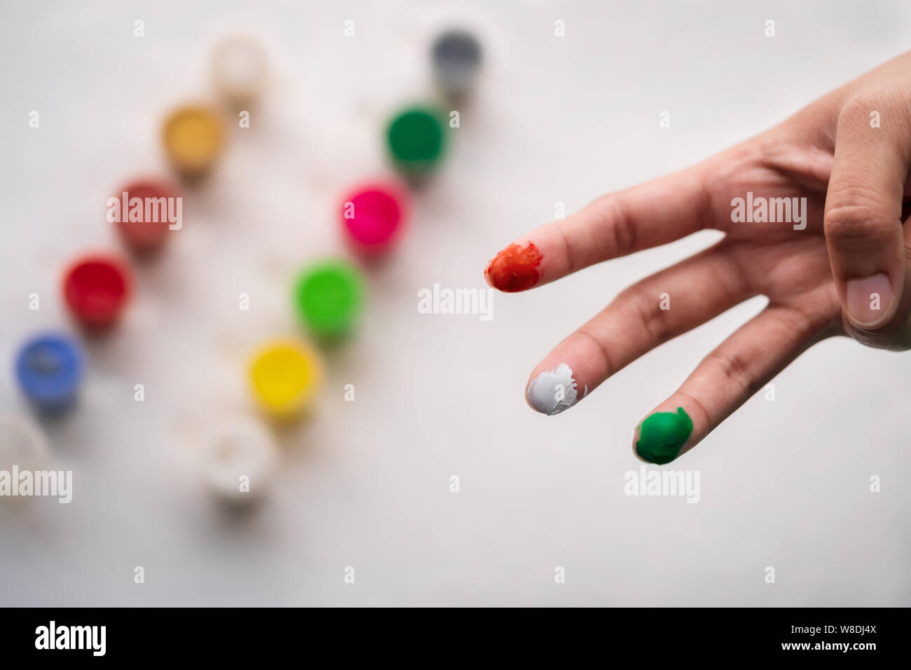 Indisches Mädchen zeigen Ihr malte tricolor Finger, top Aussicht auf weißem Hintergrund. Stockfoto