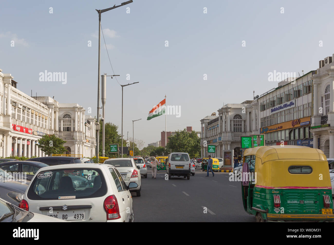 Für Fahrzeuge, die auf der Straße mit der indischen Flagge im Hintergrund am Connaught Place in Neu-Delhi Stockfoto