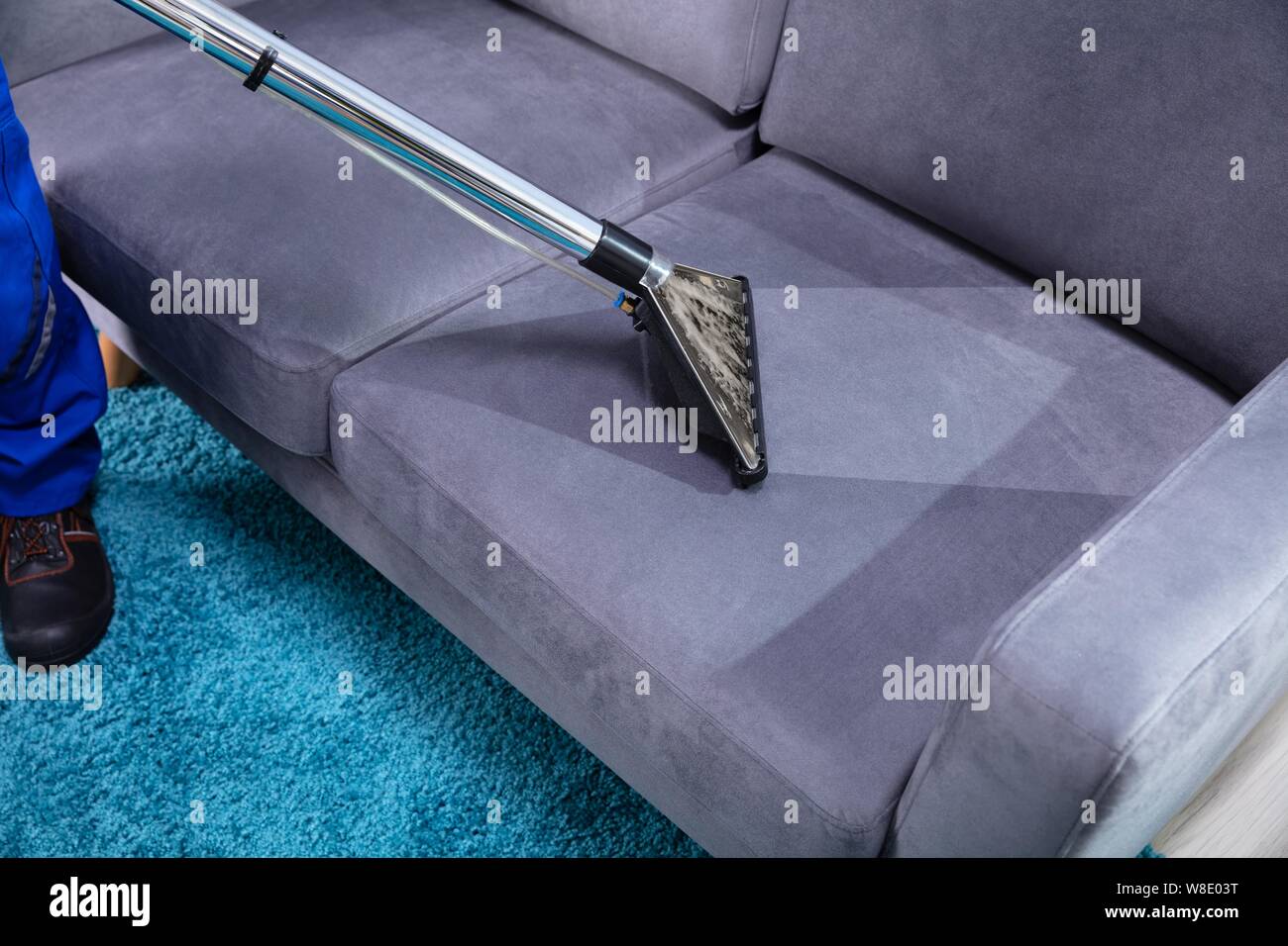Foto der Person Reinigung Sofa mit Staubsauger Stockfoto