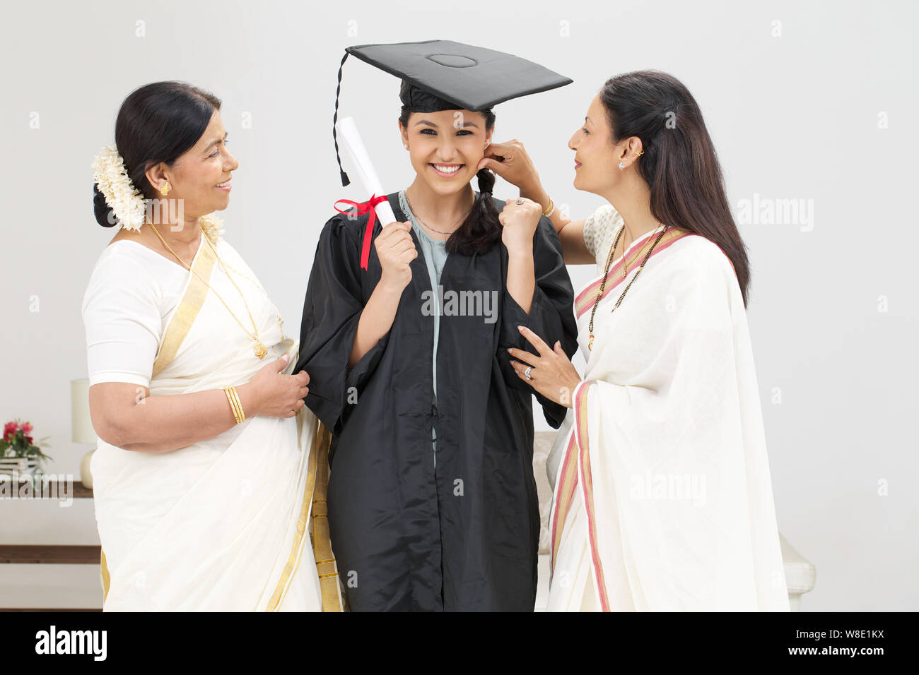 Studentin steht mit ihren Eltern und lächelt Stockfoto