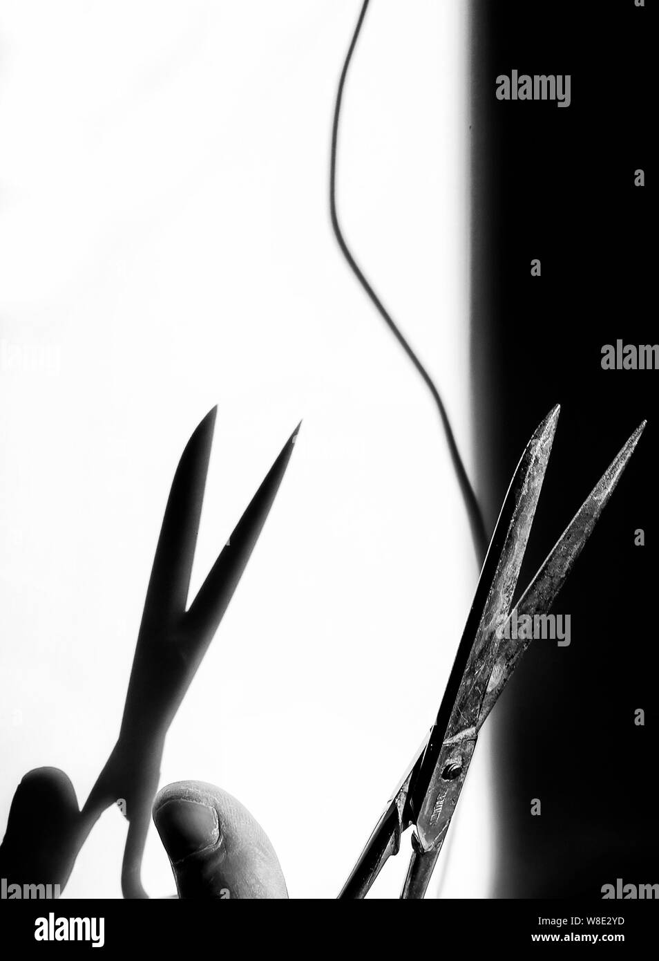 Schere aus Metall in Schwarz und Weiß sind über ein Gewinde zu schneiden, mit der Schattenwurf auf einer schwarzen und weißen Hintergrund Stockfoto