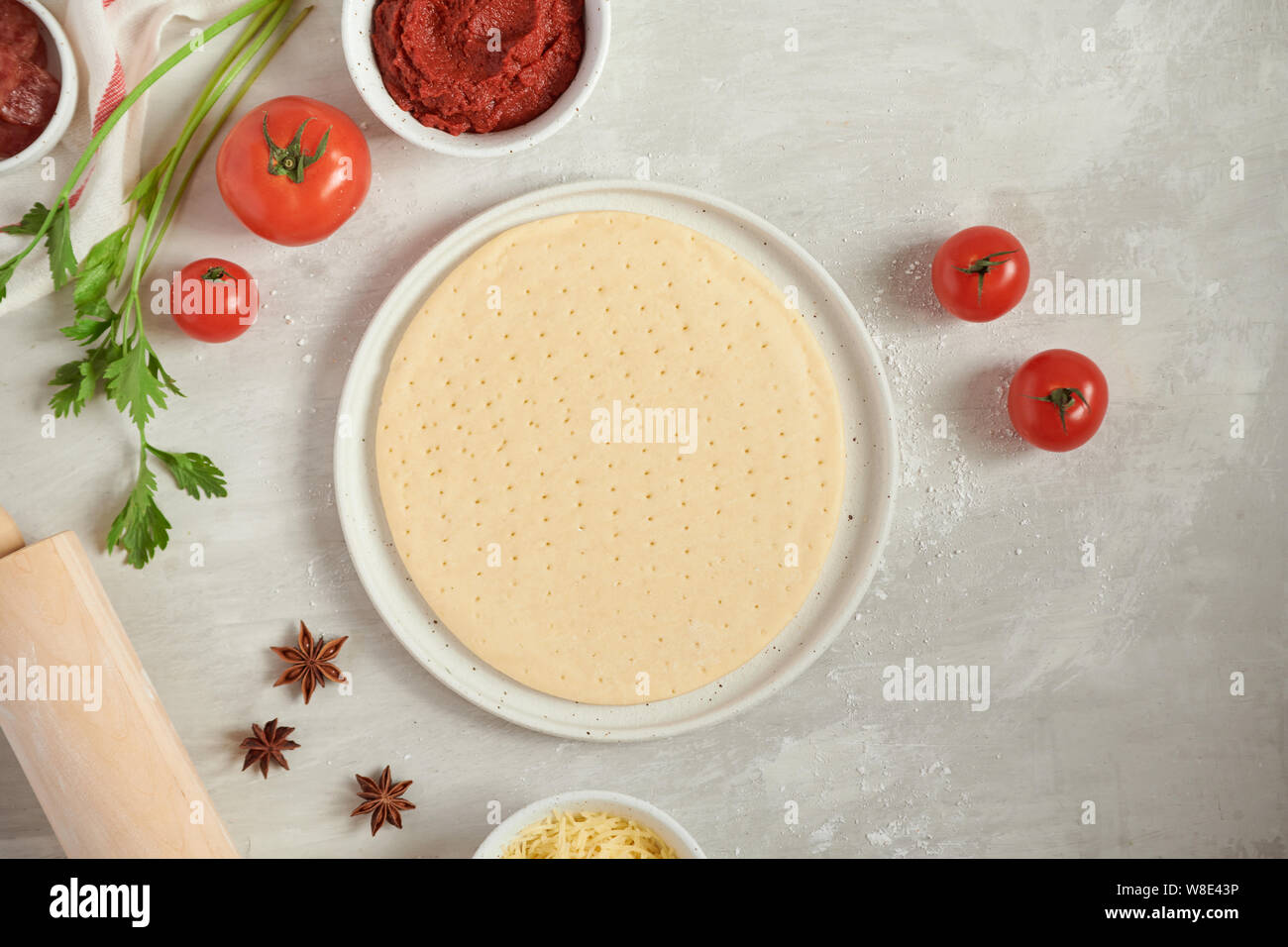 Frischen Teig pizza Base und Zutaten auf einem weißen Tisch. Ansicht von oben. Stockfoto