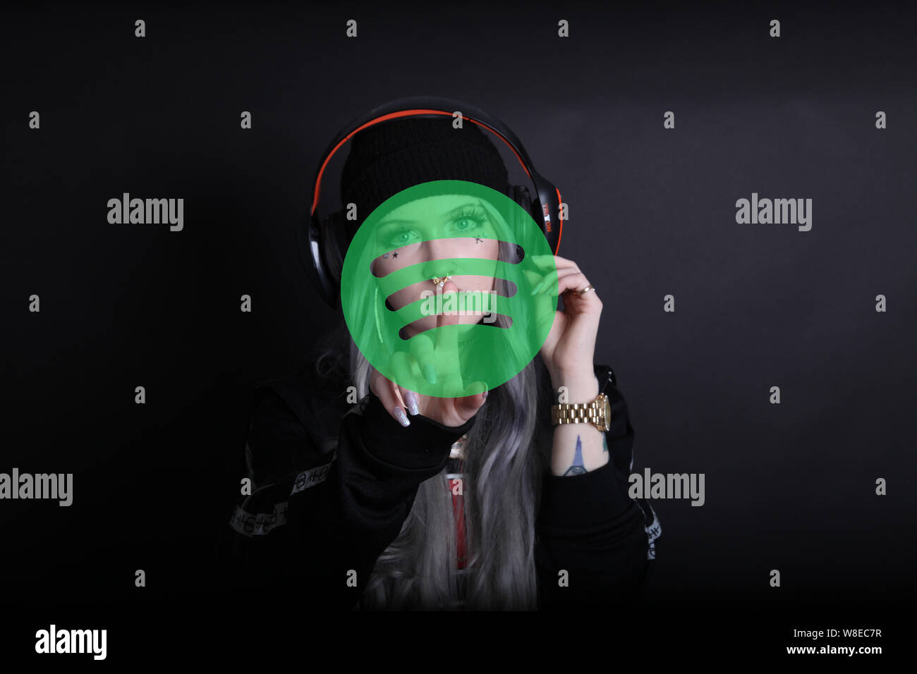 Moderne tausendjährige Interaktion mit Technologie Pressen Spotify Streaming Musik-App Tragen Kopfhörer, Handgesten, um mit der virtuellen Realität zu interagieren Stockfoto
