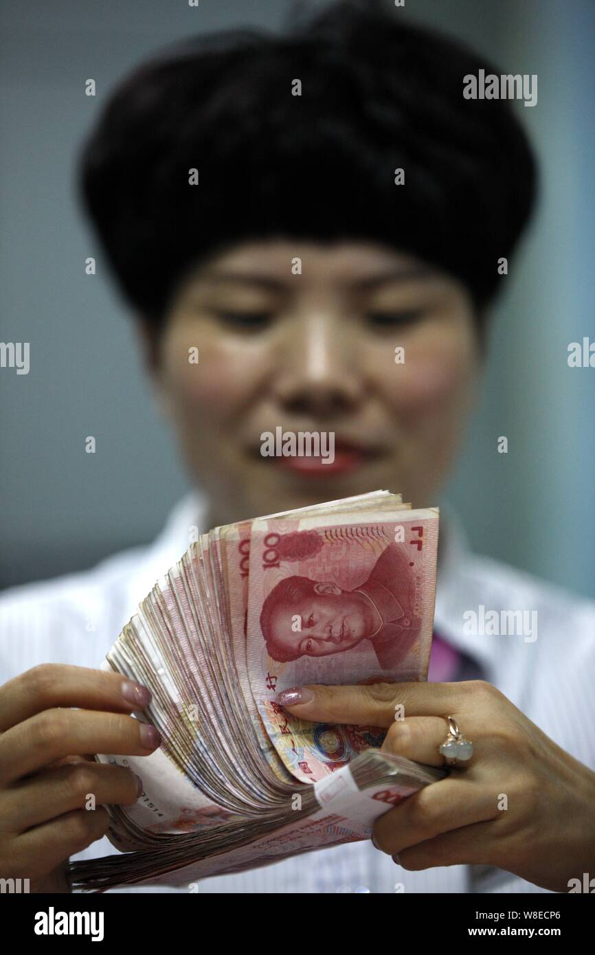 ---- Eine chinesische Angestellte zählt RMB (Renminbi) Yuan Banknote bei einer Bank in der Stadt Huaibei, der ostchinesischen Provinz Anhui, 11. August 2015. China hat starte Stockfoto