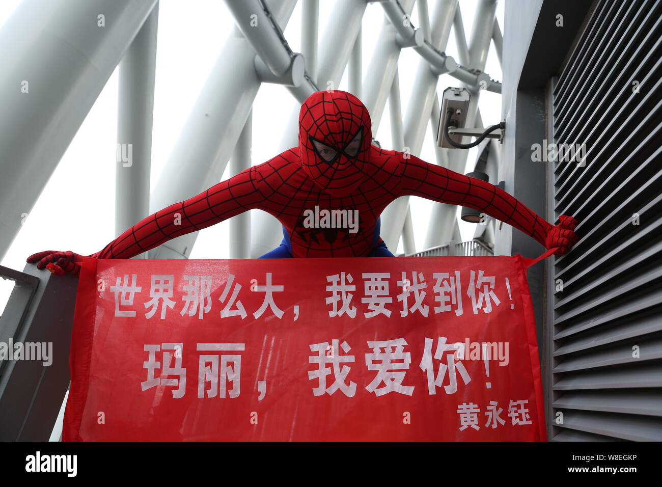 Ein Mann in der Spider-man Kostüm gekleidet posiert mit einem Banner auf der Kanton Tower zu seiner Freundin in der Stadt Guangzhou vorzuschlagen, der South China Guangdon Stockfoto