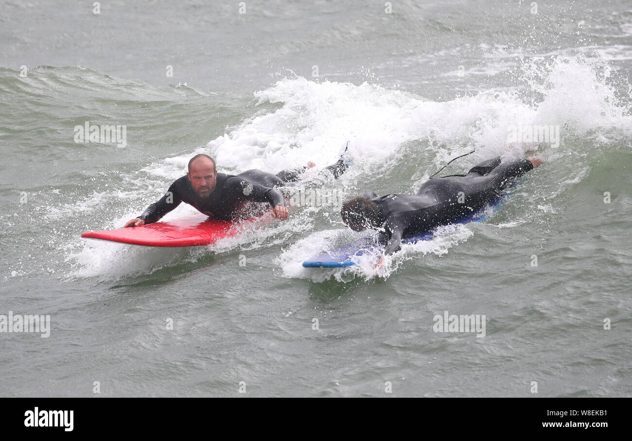 Zwei surfer Fahrt eine Welle aus Bournemouth Strand in Dorset. Warnungen für Regen und Wind in Kraft trat heute in fast allen UK. Stockfoto