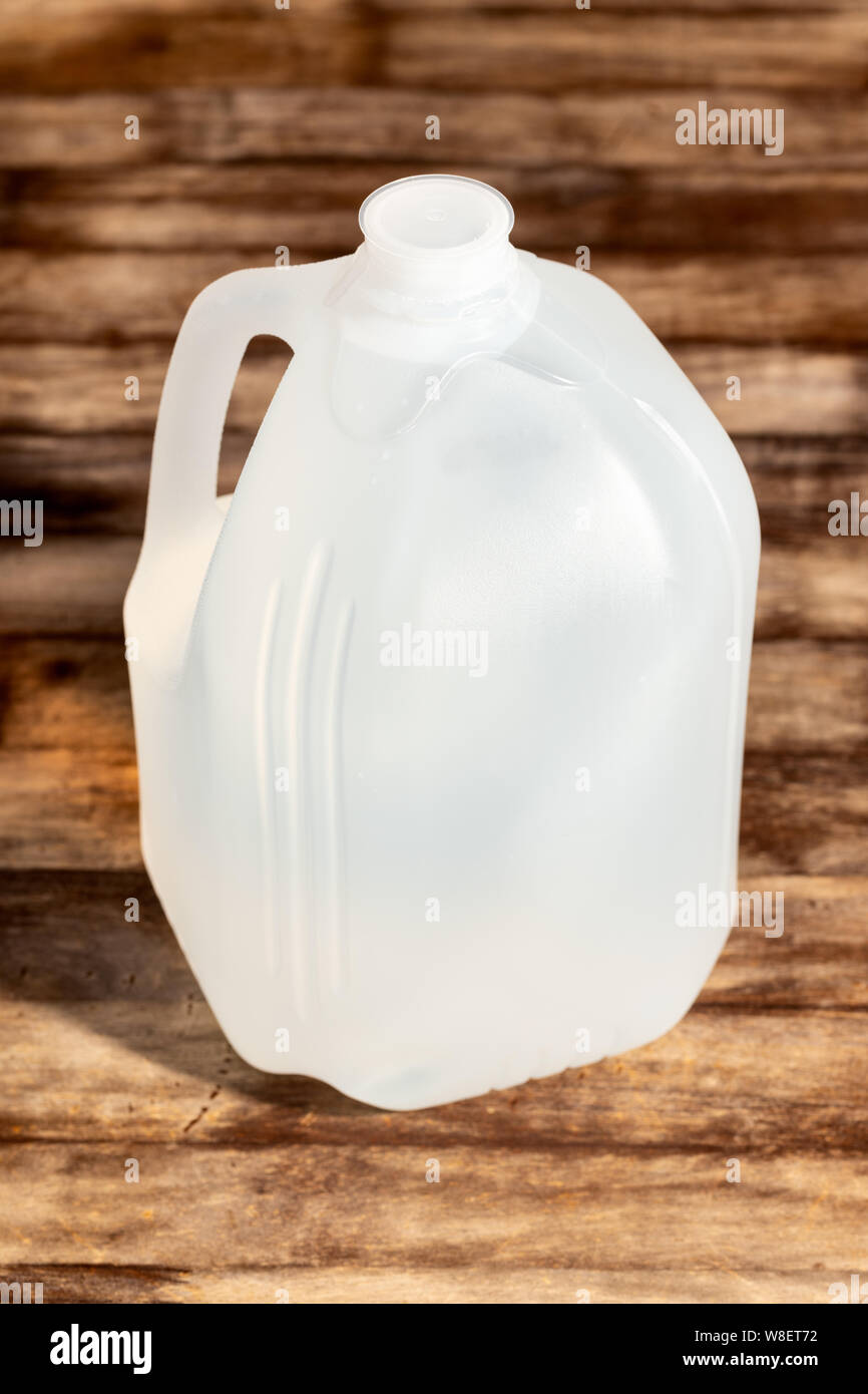 Leere Verpackungen Kunststoff weiß Gallone auf hölzernen Tisch Hintergrund isoliert. Stockfoto