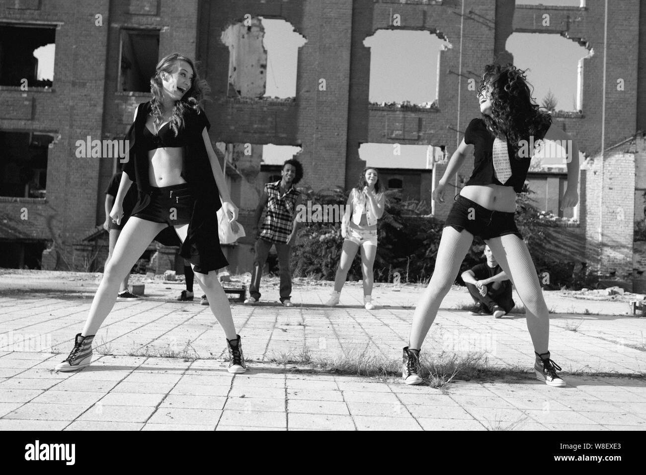 Zwei junge Mädchen Straße tanzen in einem städtischen Platz Durchführen einer energetischen Routine der hip hop Moves beleuchtet durch eine helle Sonne, Low Angle View. Stockfoto