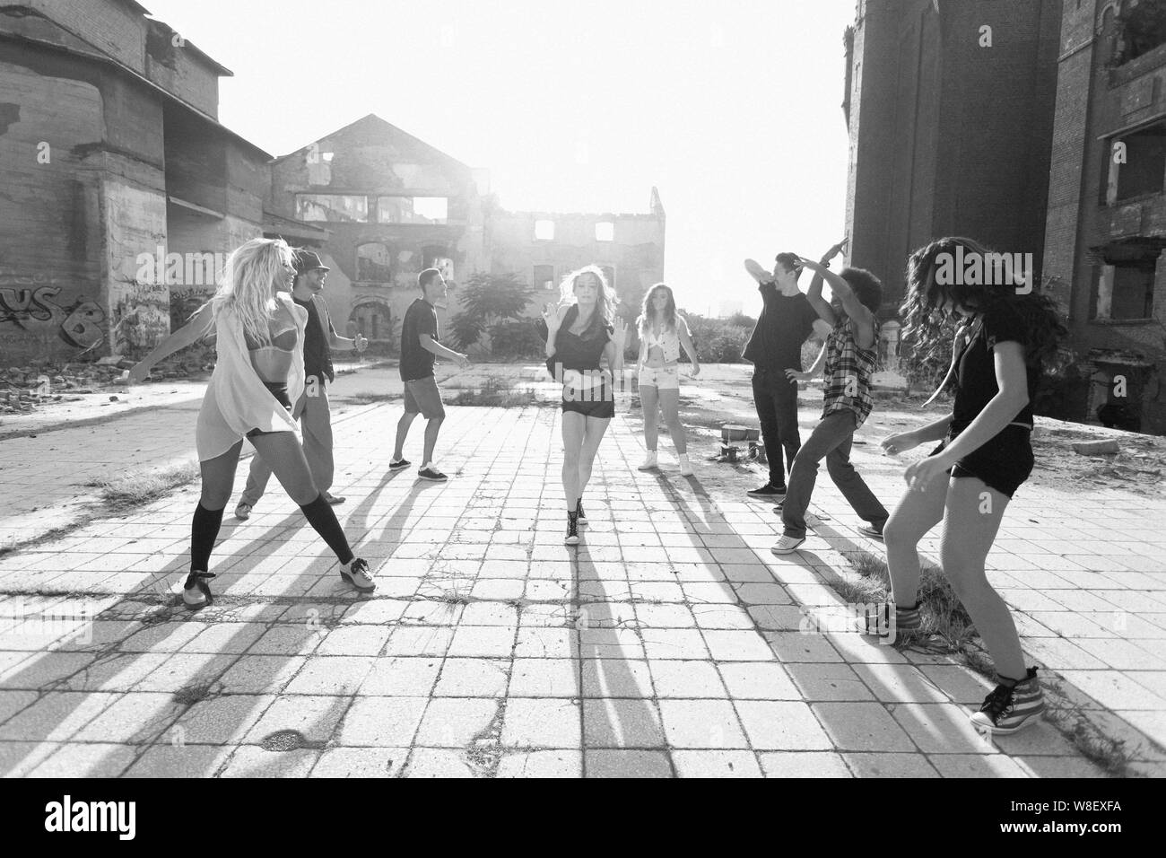 Energische junge Leute hip hop street Tänzer ihre routinemäßige Durchführung in einem städtischen Platz mit Hintergrundbeleuchtung durch eine helle Sonne flare über Hochhäuser Stockfoto