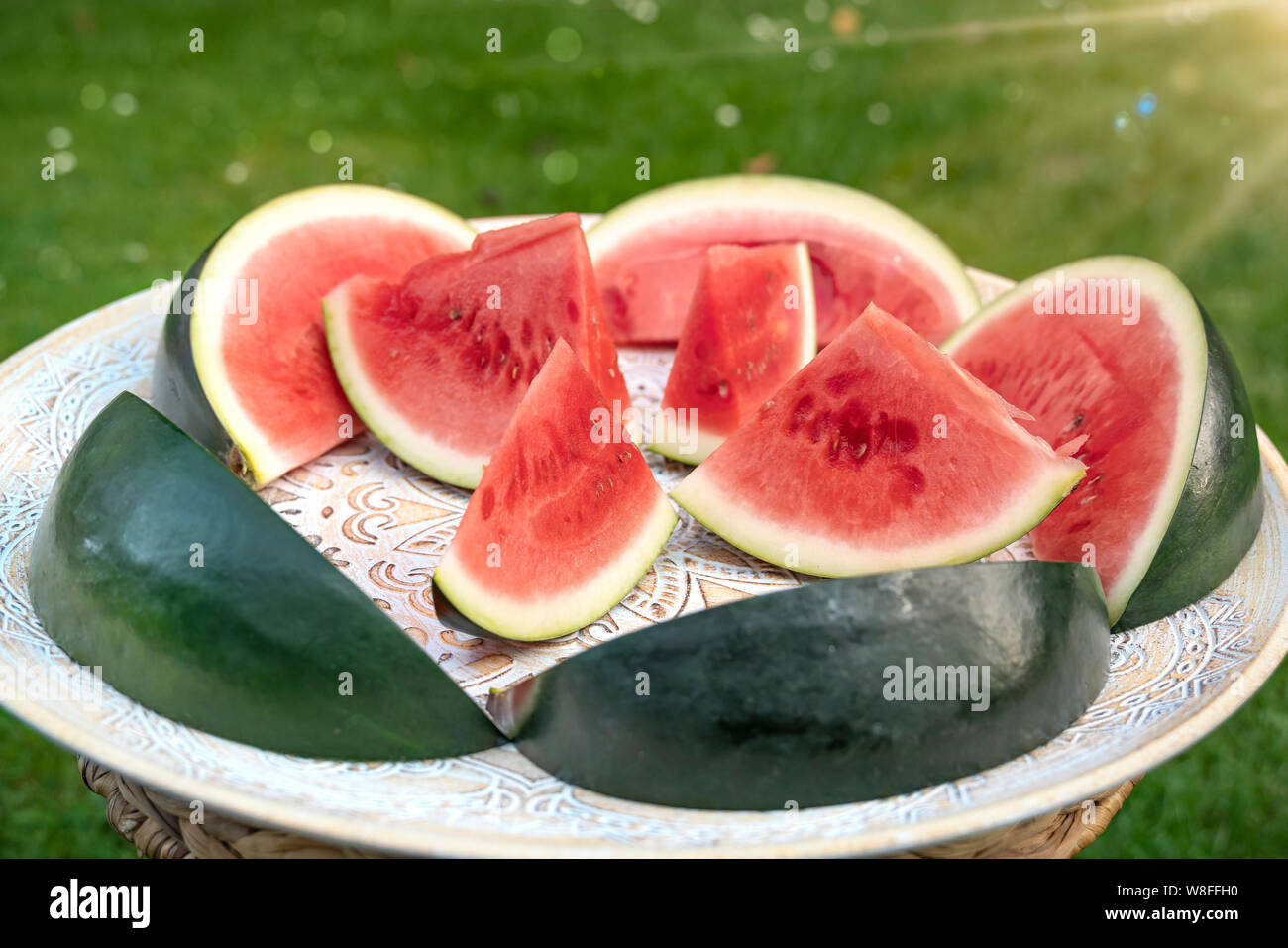 Melonen Stücke, wie Schiffe aussehen liegen auf einer afrikanischen Holz- fach Die Melonen stehen auf der grünen Wiese sind mit Sonnenschein. Stockfoto
