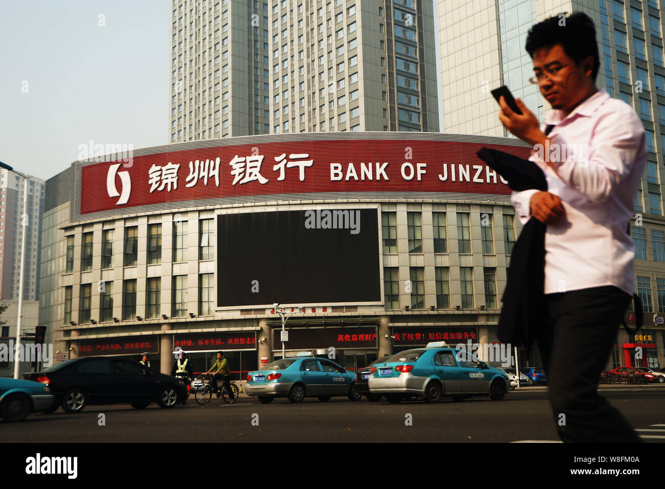 ---- Eine Fußgängerzone nutzt sein Handy, als er an eine Filiale der Bank von Jinzhou in Tianjin, China, 16. Oktober 2015. Bank von Jinzhou hat gewonnen Stockfoto