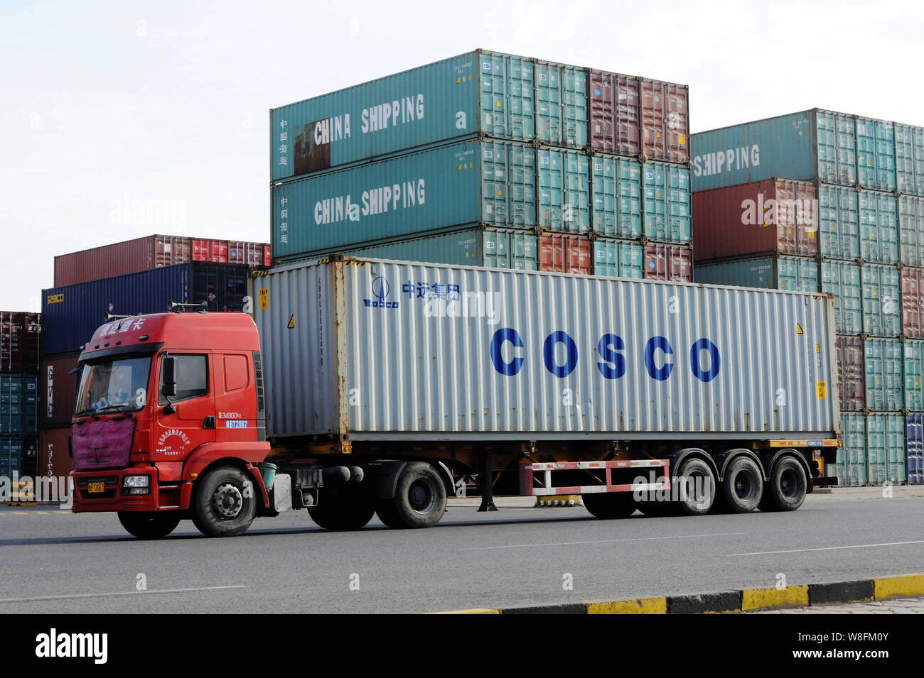 ---- Ein Lkw mit einem Container der Cosco passiert einen Stapel von Container von China Shipping im Hafen von Qingdao in Qingdao Stadt geladen, East China" Stockfoto