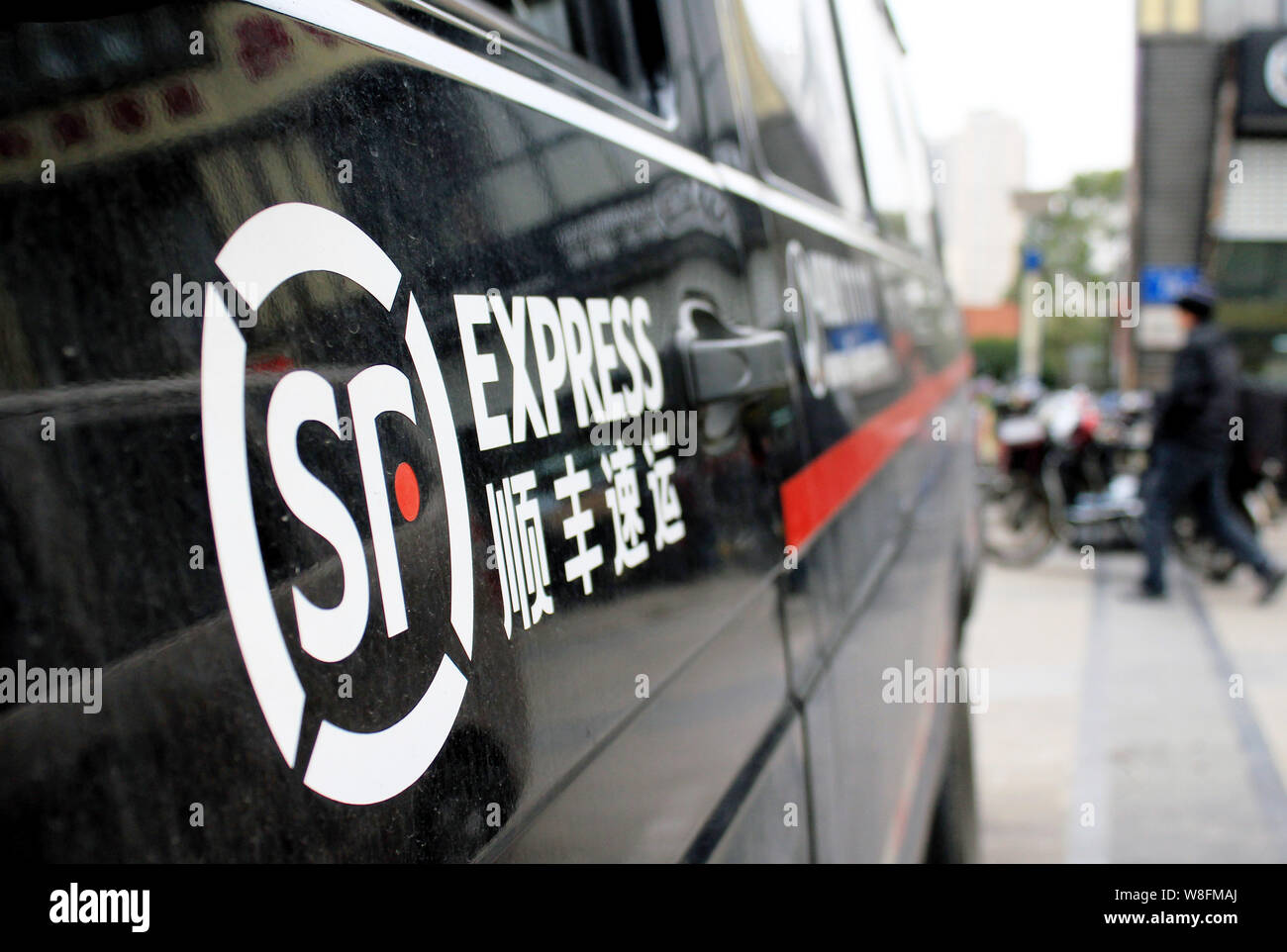 Ein Fußgänger geht hinter einem lieferfahrzeug von SF Express in Nanjing, Provinz Jiangsu, China vom 1. Februar 2015. SF Express, einem führenden Kinn Stockfoto