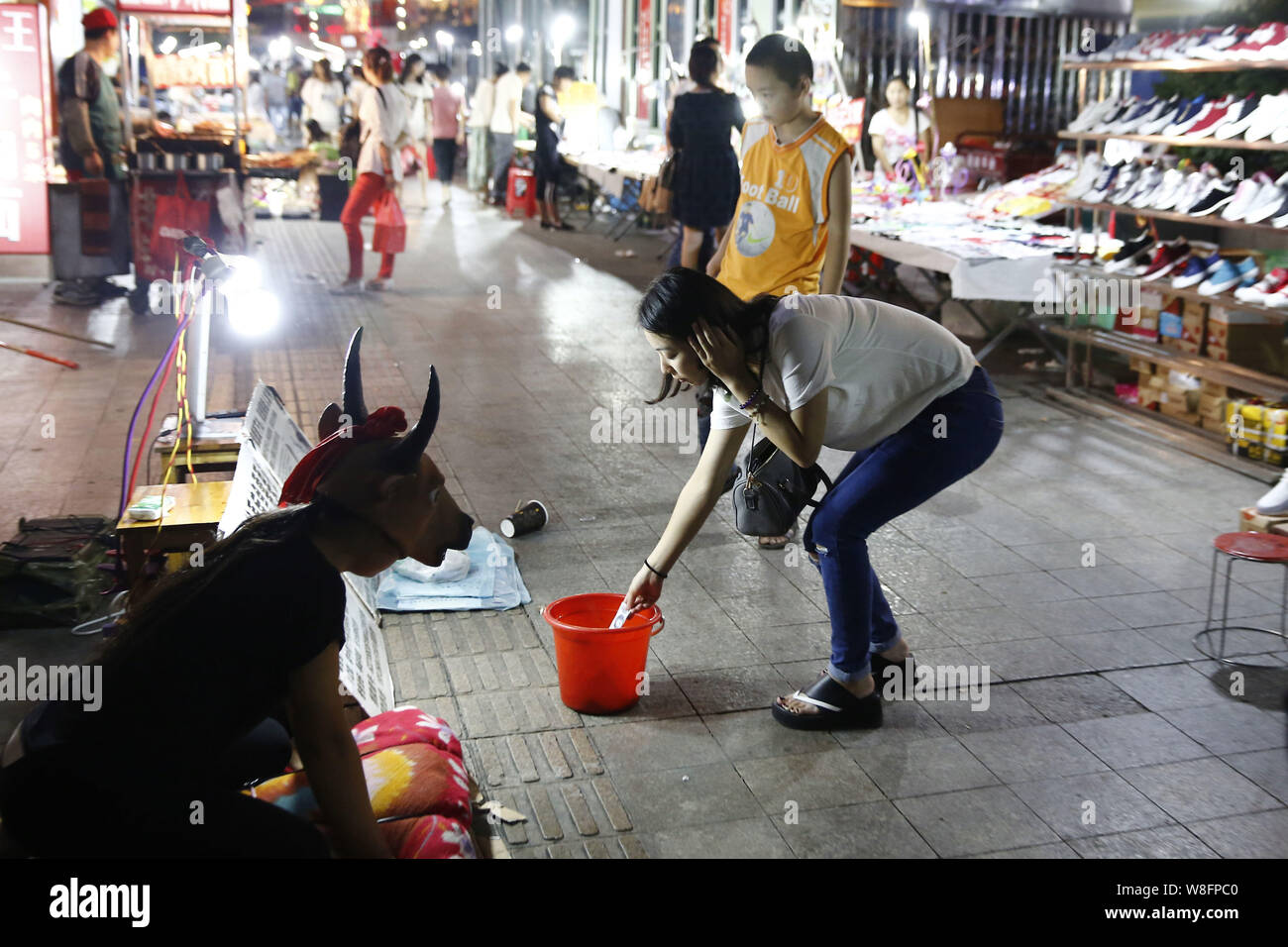 Der 15-jährige Hao Elhazray ahmed Hamadi (Alias), Links, in Kuh Kostüm gekleidet, bettelt auf der Straße Geld für medizinische Kosten ihres Vaters in Hefei City zu erhöhen, Stockfoto