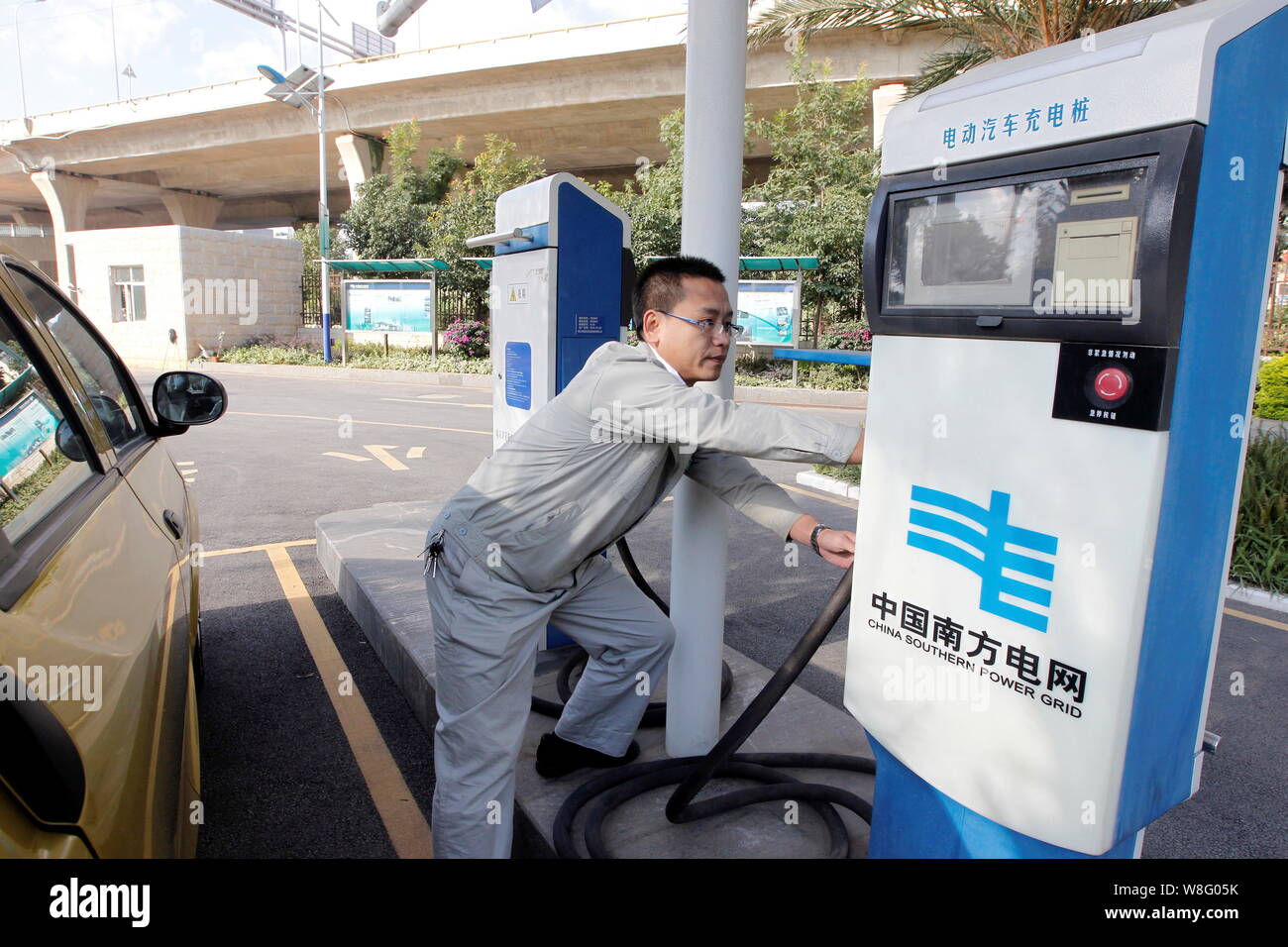 ---- Ein Arbeitnehmer zieht einen Stecker mit einem Auto an einer Charing von China Southern Power Grid in Kunming City zu tanken, im Südwesten der chinesischen Provinz Yunnan, Stockfoto