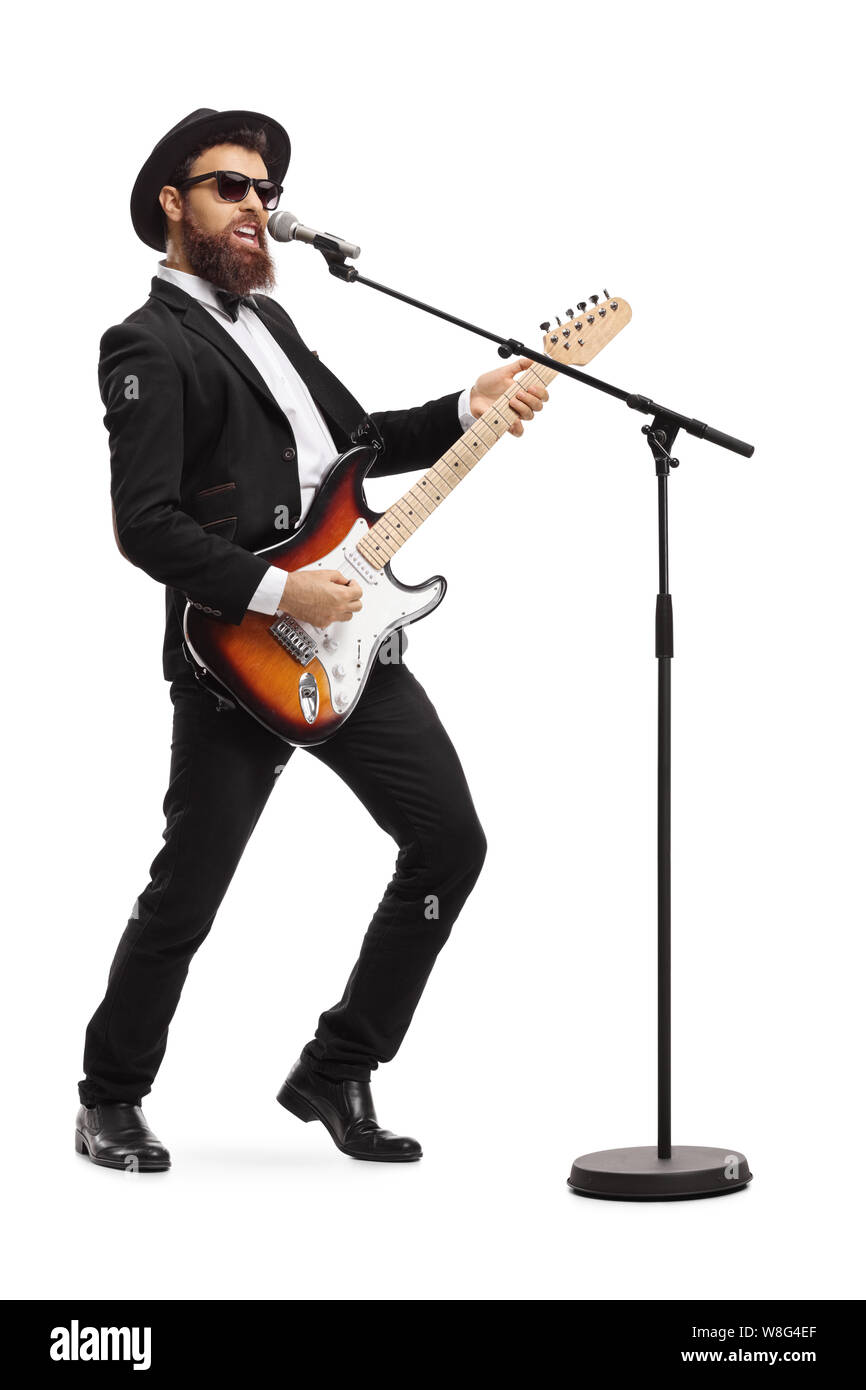 Volle Länge geschossen von einem männlichen Künstler singen auf ein Mikrofon und eine E-Gitarre auf weißem Hintergrund Stockfoto