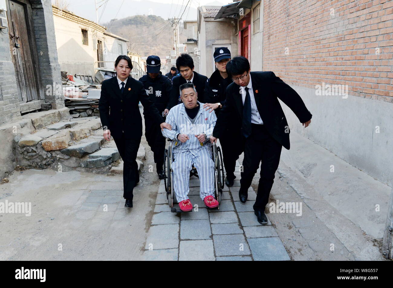 Die chinesische Polizei und Gericht Offiziere an den Patienten mit dem Rollstuhl zu seinem Haus in Peking, China Chen Zunamen, 10. Februar 2015. Ein Patient, der sein Stockfoto