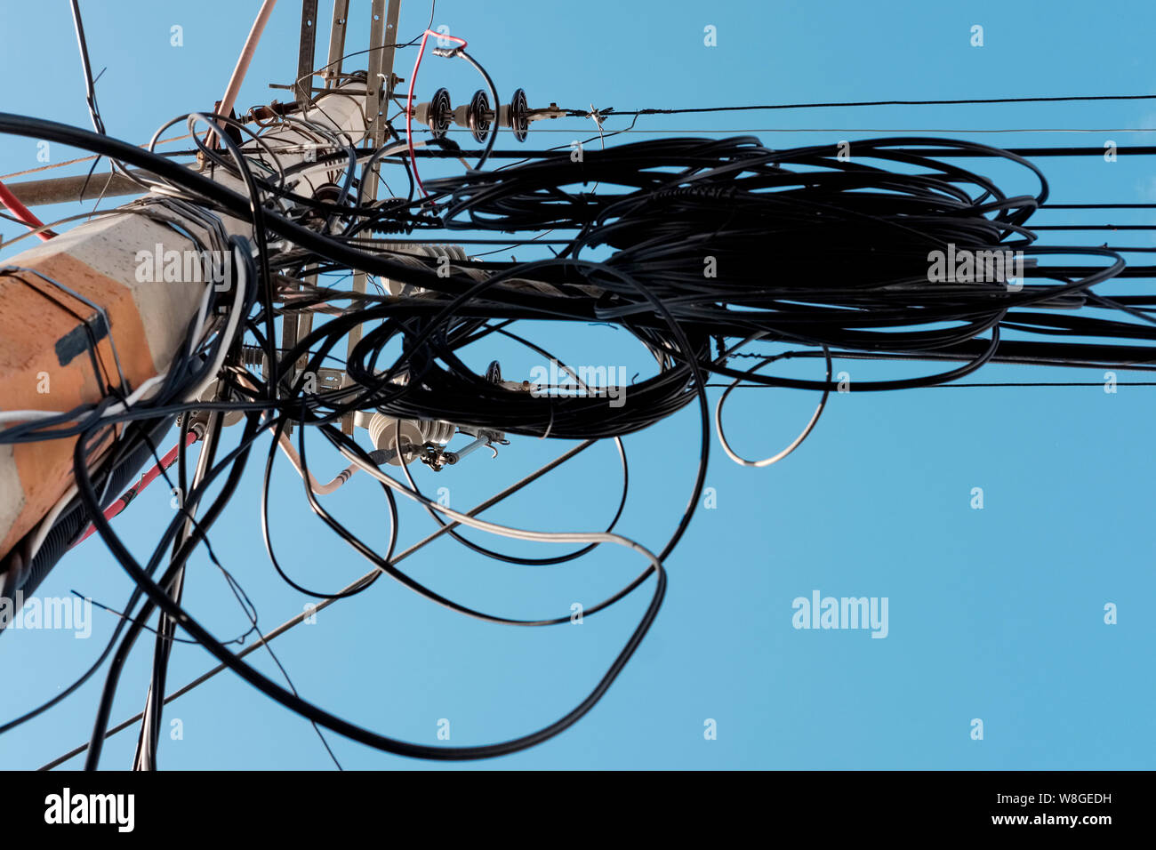Elektrische Pole mit vielen und disordly Kabel. Entgegengesetzte Ansicht eines elektrischen Pol mit blauen Himmel im Hintergrund. Stockfoto