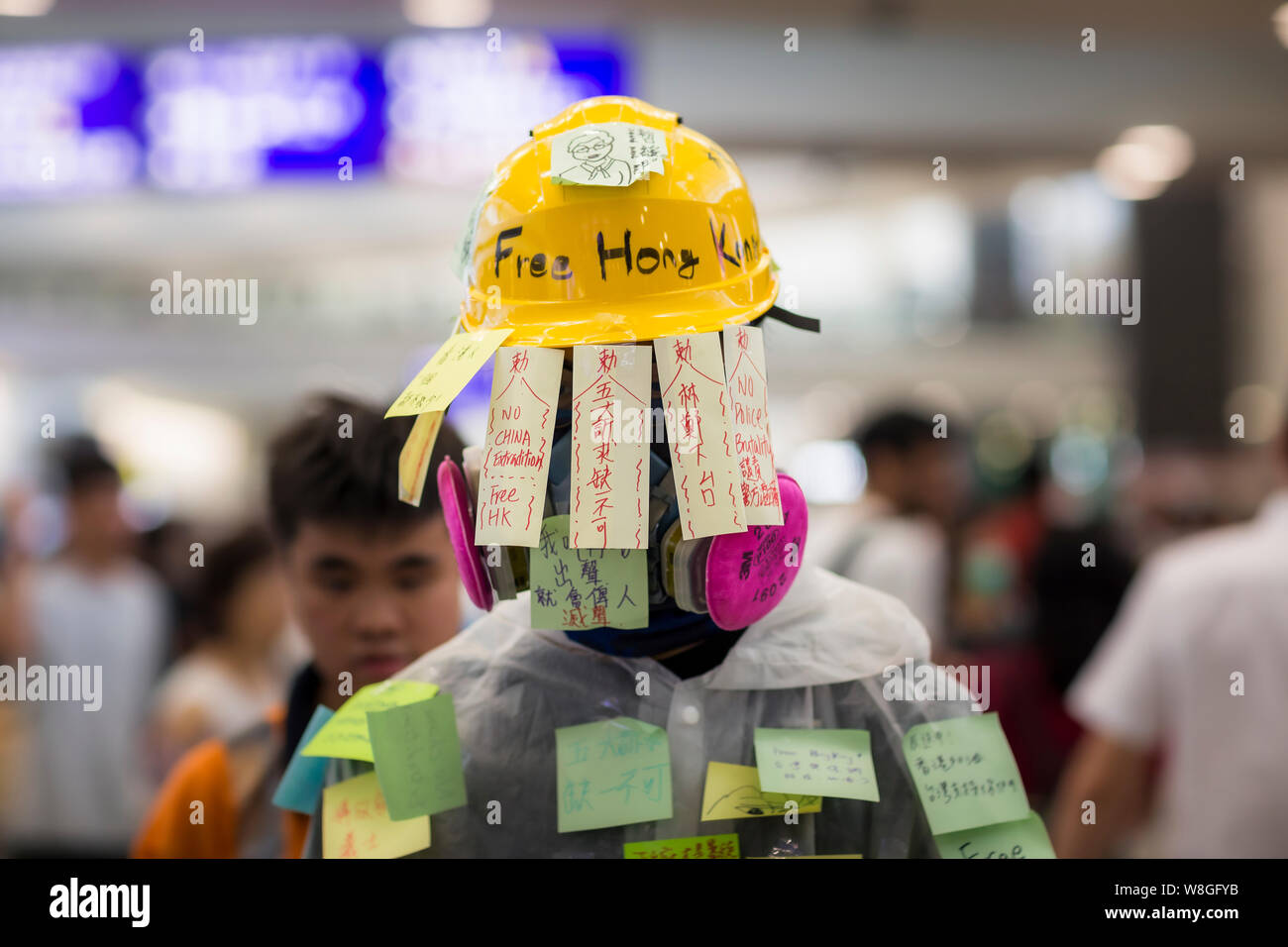 Eine Demonstrantin Handeln eine menschliche Lennon-mauer andere post-Meldungen auf seinem Körper während des Protestes am Flughafen zu lassen. Tausende Demonstranten in der Ankunftshalle des internationalen Flughafen Hong Kong unter der Bezeichnung "Grüße aus HKers Versammlung" die Aufmerksamkeit der internationale Reisende, die gerade in Hongkong über die aktuellen Unruhen in der Stadt gelandet zu fangen. Stockfoto