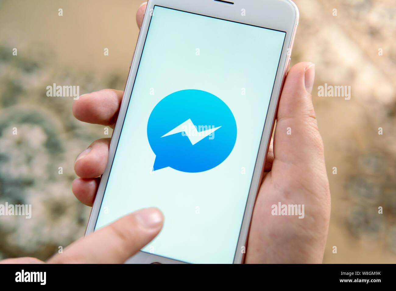 Weibliche hand mit Apple Handy mit Logo der Social Media Facebook Messenger. Social media Symbol. Kann als Illustration für Nachrichten oder Medien Konzept verwendet werden. Stockfoto