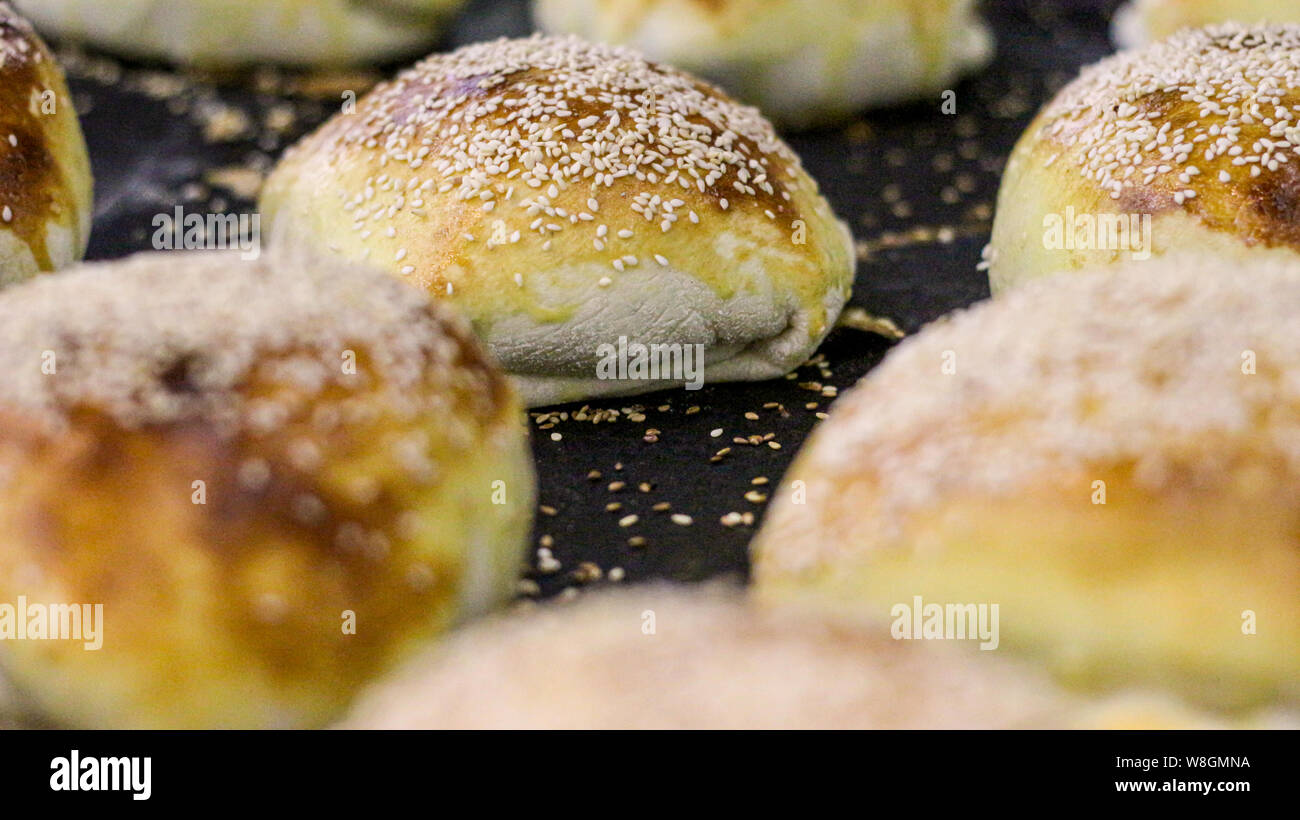 Einige Pizza Brot mit Sesam auf einem schwarzen Fach Stockfoto