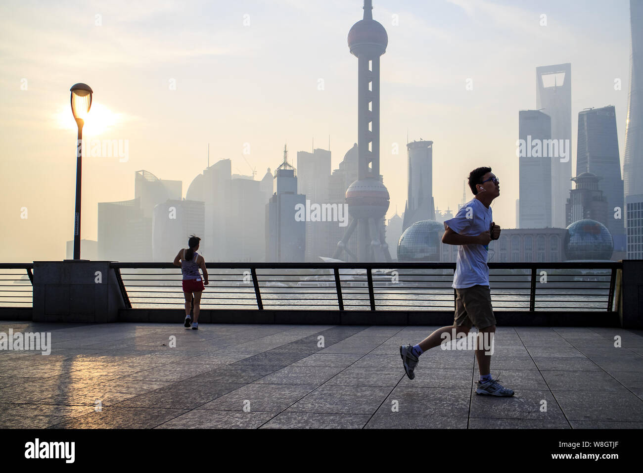 ---- Eine chinesische Jogger läuft mit der Promenade am Bund gegen die Skyline von Pudong das Finanzviertel Lujiazui mit Wolkenkratzer in Shanghai, C Stockfoto