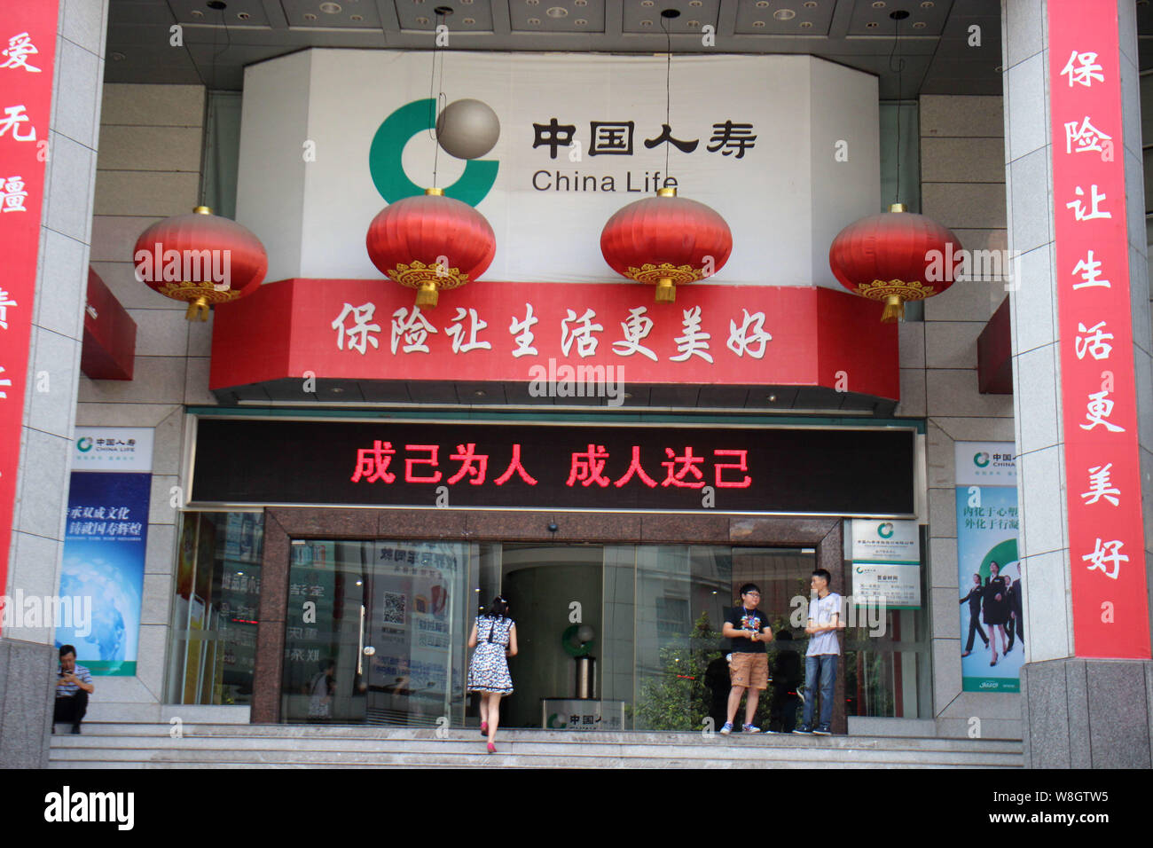 ---- Ein Kunde geht auf eine Filiale der China Life Insurance in Chongqing, China, 6. August 2015. Chinas Versicherungen posted a 19,5 Pro Stockfoto