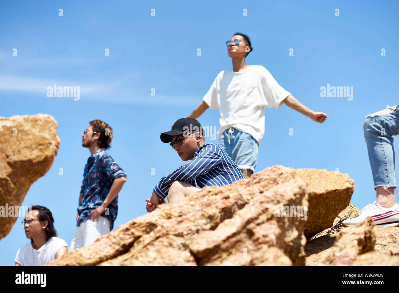 Gruppe von jungen asiatischen erwachsene Männer auf Felsen gegen den blauen Himmel Sonne und frische Luft genießen. Stockfoto
