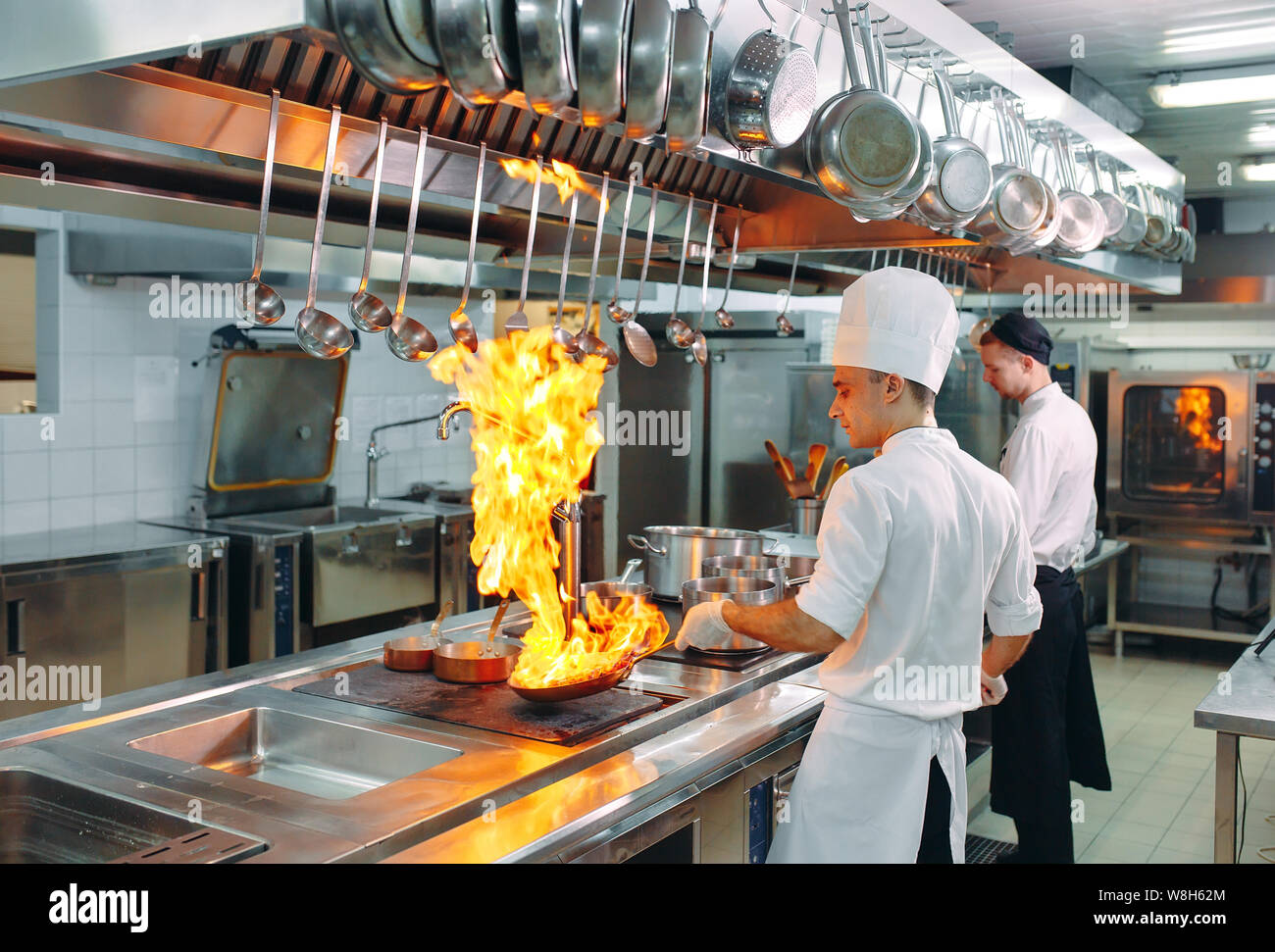 Moderne Küche. Köche bereiten Mahlzeiten auf dem Herd in der Küche des Restaurant oder Hotel. Das Feuer in der Küche. Stockfoto