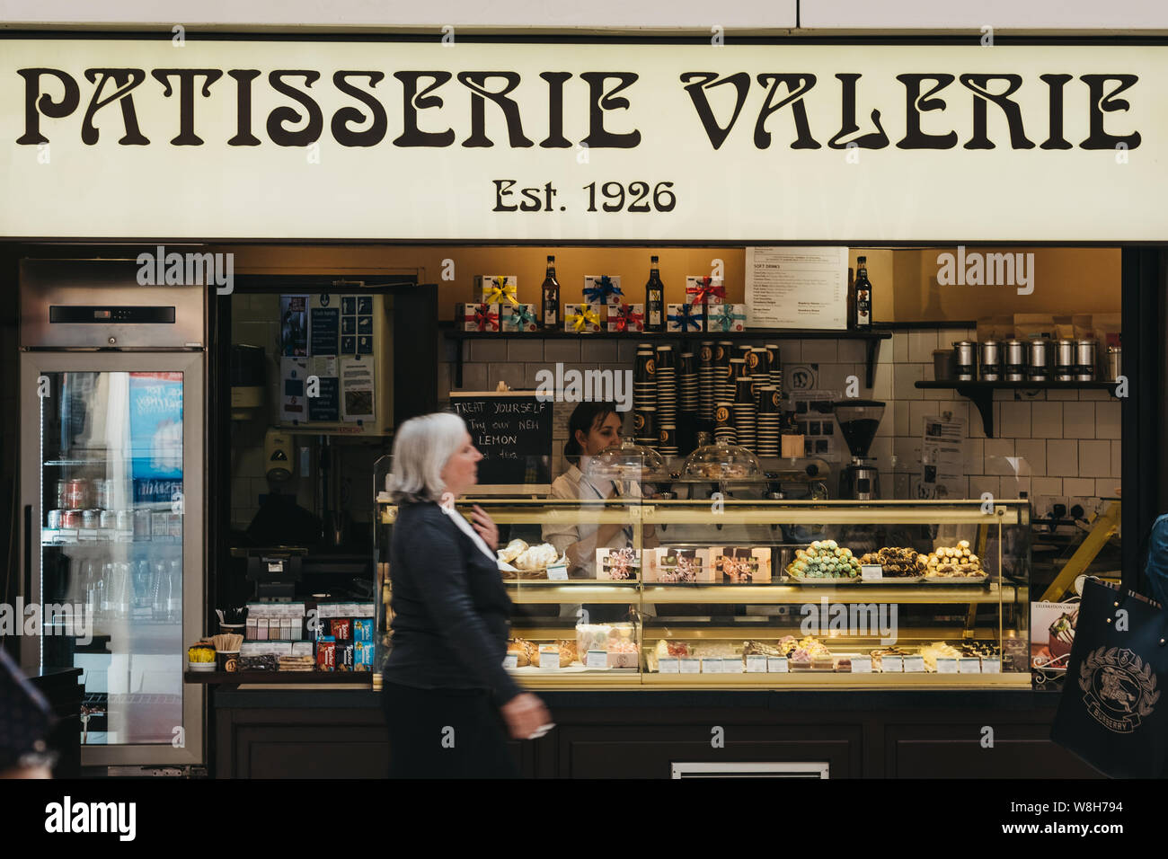 London, Großbritannien - 16 Juli, 2019: Frau geht Vergangenheit Patisserie Valerie stand in London Victoria Station. Patisserie Valerie ist ein beliebtes Kette der Coffee Shop Stockfoto