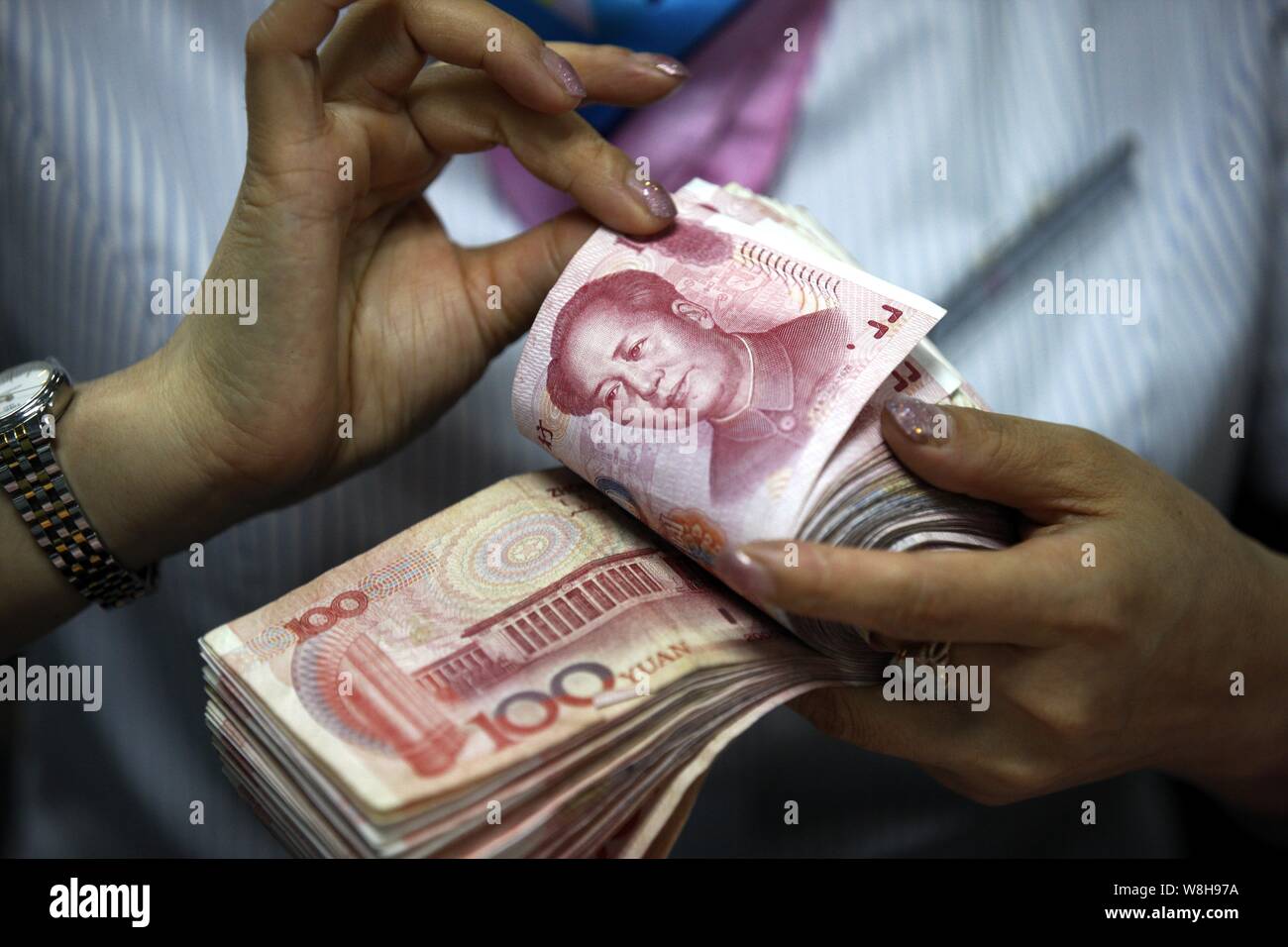 ---- Eine chinesische Angestellte zählt RMB (Renminbi) Yuan Banknote bei einer Bank in der Stadt Huaibei, der ostchinesischen Provinz Anhui, 11. August 2015. China hat starte Stockfoto