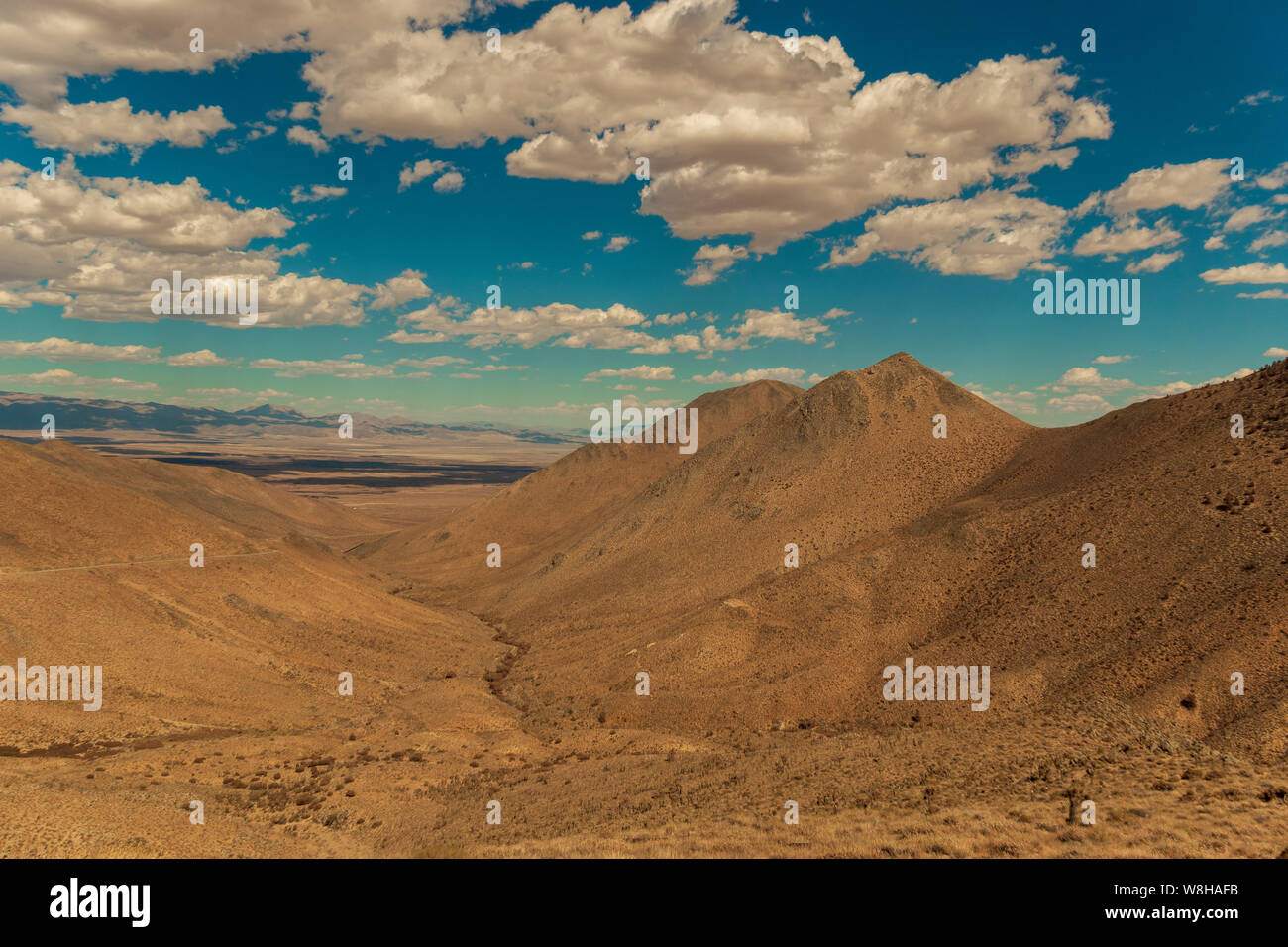 Braun Canyon und Berge mit spärlichen tote Vegetation unter strahlend blauen Himmel mit weißen flauschigen Wolken. südlichen Berge der Sierra Nevada, Mojave Wüste. Stockfoto
