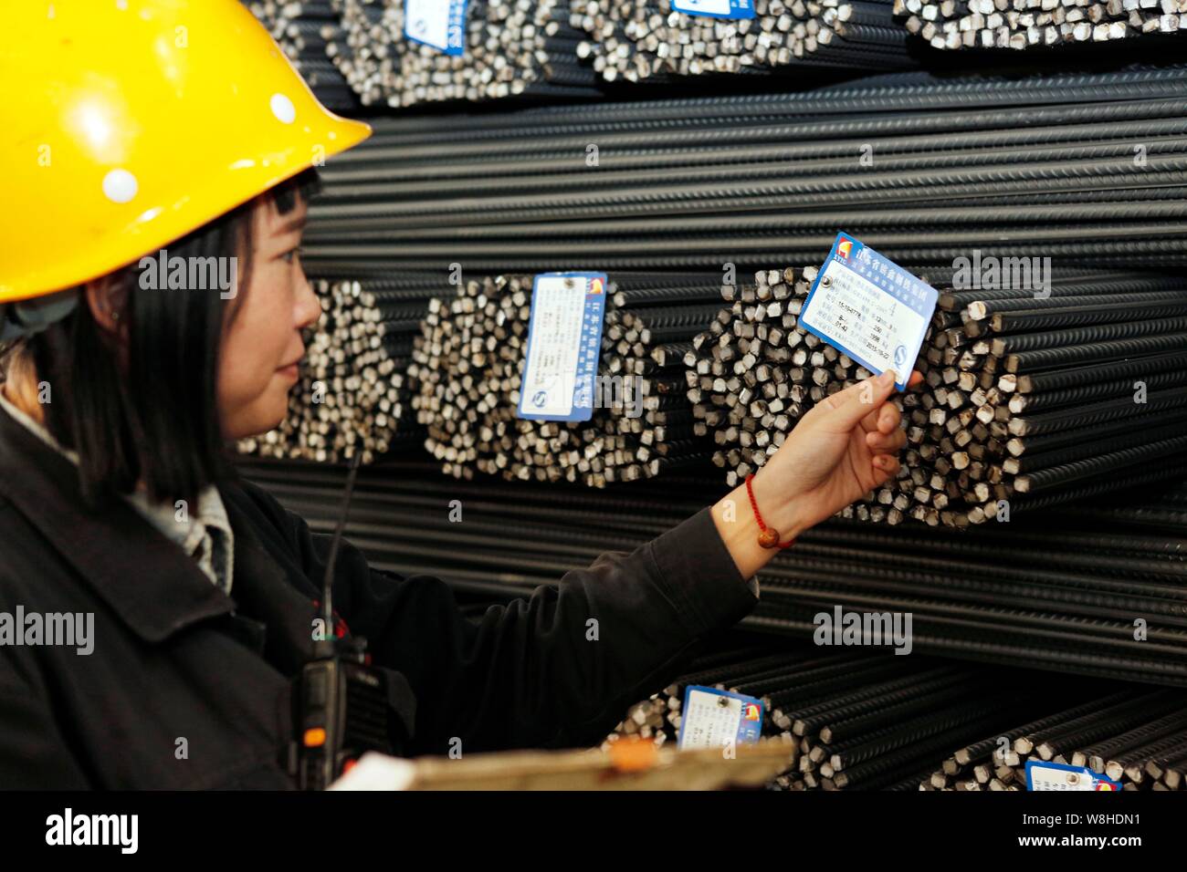 ---- Eine weibliche chinesischer Arbeiter prüft Etiketten vom Verstärken von Stahl Stäbe im Lager eines Stahlwerks in Lanzhou, China Jiangsu pr Stockfoto