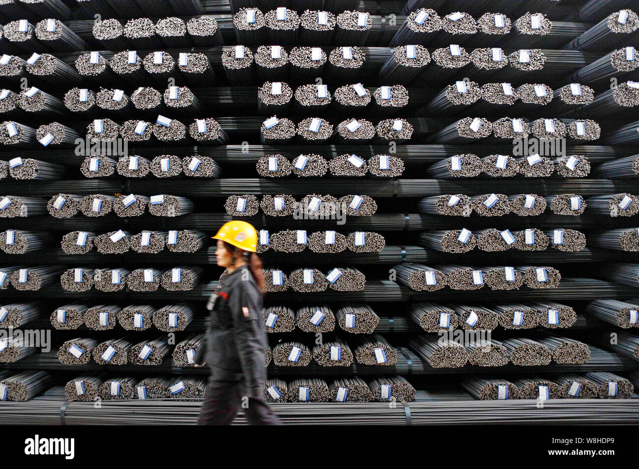 Ein weiblicher chinesischer Arbeiter Spaziergänge letzten Stapel vom Verstärken von Stahl Stäbe im Lager eines Stahlwerks in Lanzhou City, East China Jiangsu provin Stockfoto