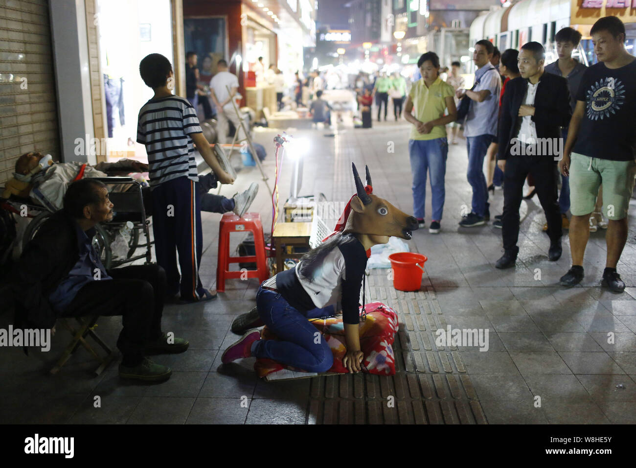 Der 15-jährige Hao Elhazray ahmed Hamadi (Alias), Center, in Kuh Kostüm gekleidet, bettelt auf der Straße Geld für medizinische Kosten ihres Vaters in Hefei City zu erhöhen Stockfoto