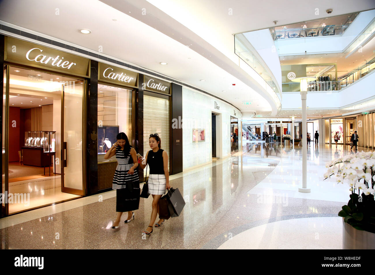 ------ Moderne, junge Frauen, die einkaufstaschen Spaziergang, vorbei an der Boutique von Cartier auf der Plaza 66 Shopping Mall in Shanghai, China, 1. September 2015 Stockfoto