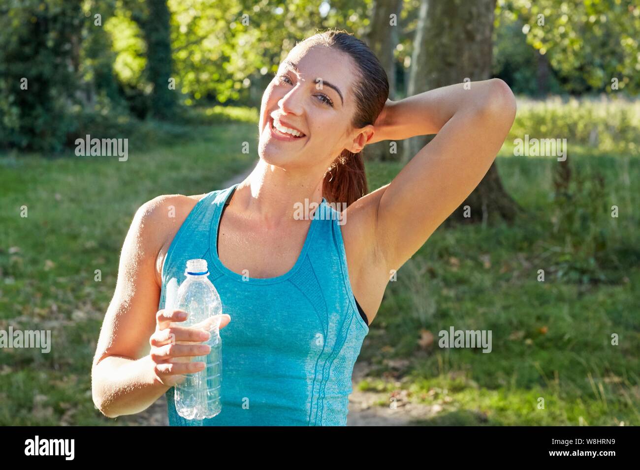Junge Frau mit Wasserflasche lächelnd, Portrait. Stockfoto