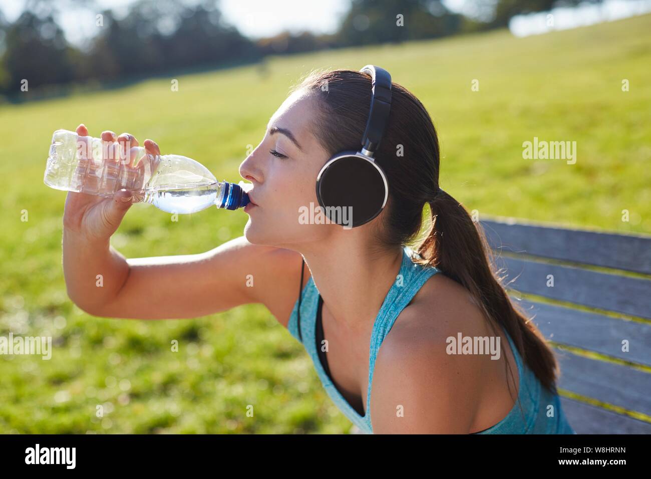 Junge Frau mit Kopfhörern Trinkwasser. Stockfoto