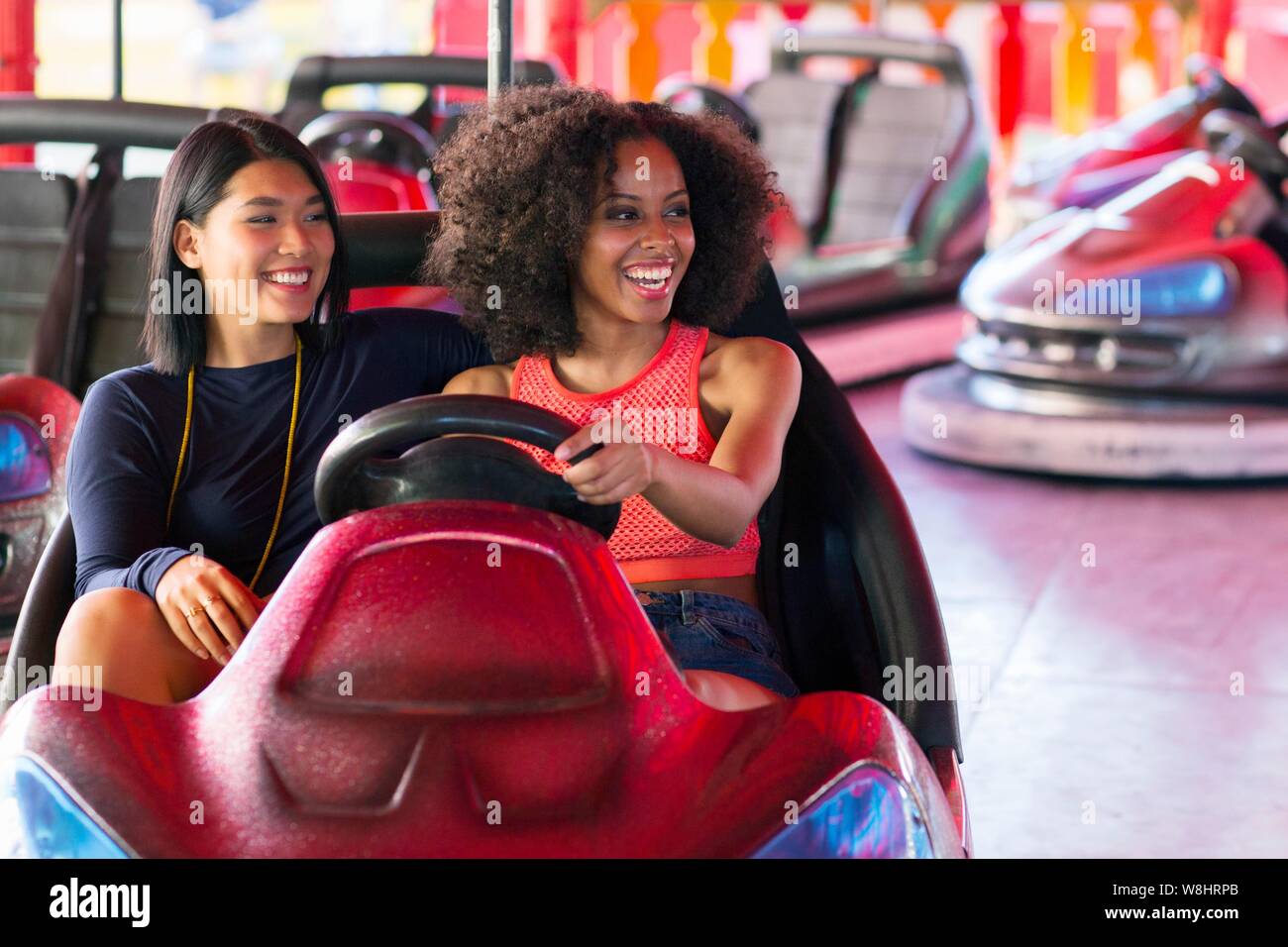 Zwei junge Frauen am Stoßfänger Auto an Kirmes. Stockfoto