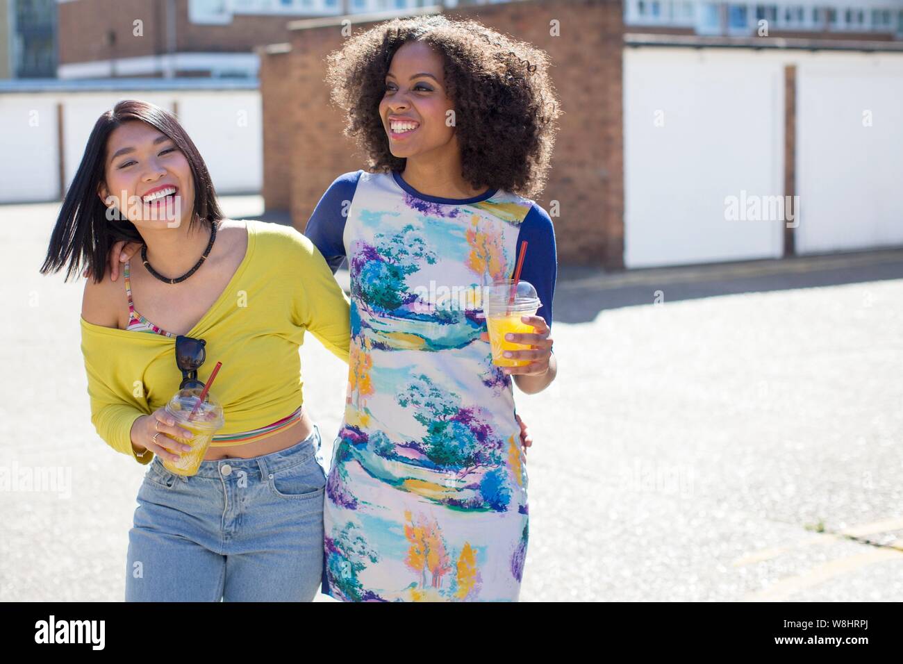 Zwei junge Frauen mit Getränken im Freien, Lachen. Stockfoto