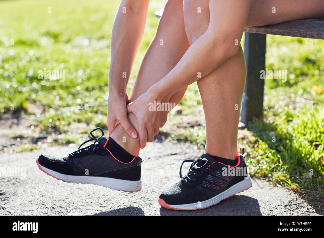 Frau trägt Trainer ihren Knöchel Holding. Stockfoto